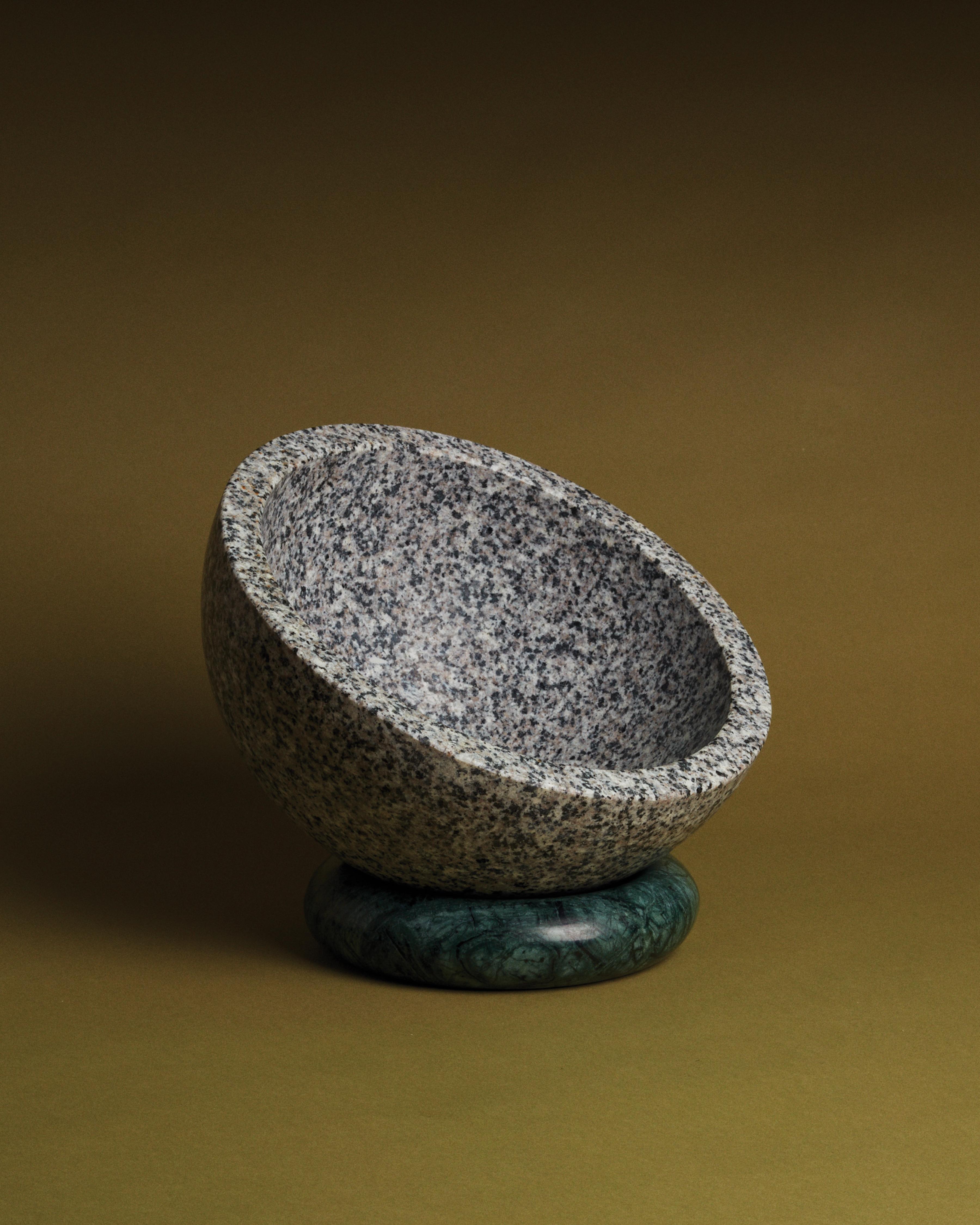 Roost bowl is a speckled granite bowl that rests on top of its marble donut base. The bowl can be turned and tilted, angled to dis- play its contents, objects, fruits and vegetables. Disassembled, it can become sculptural objects and the donut can