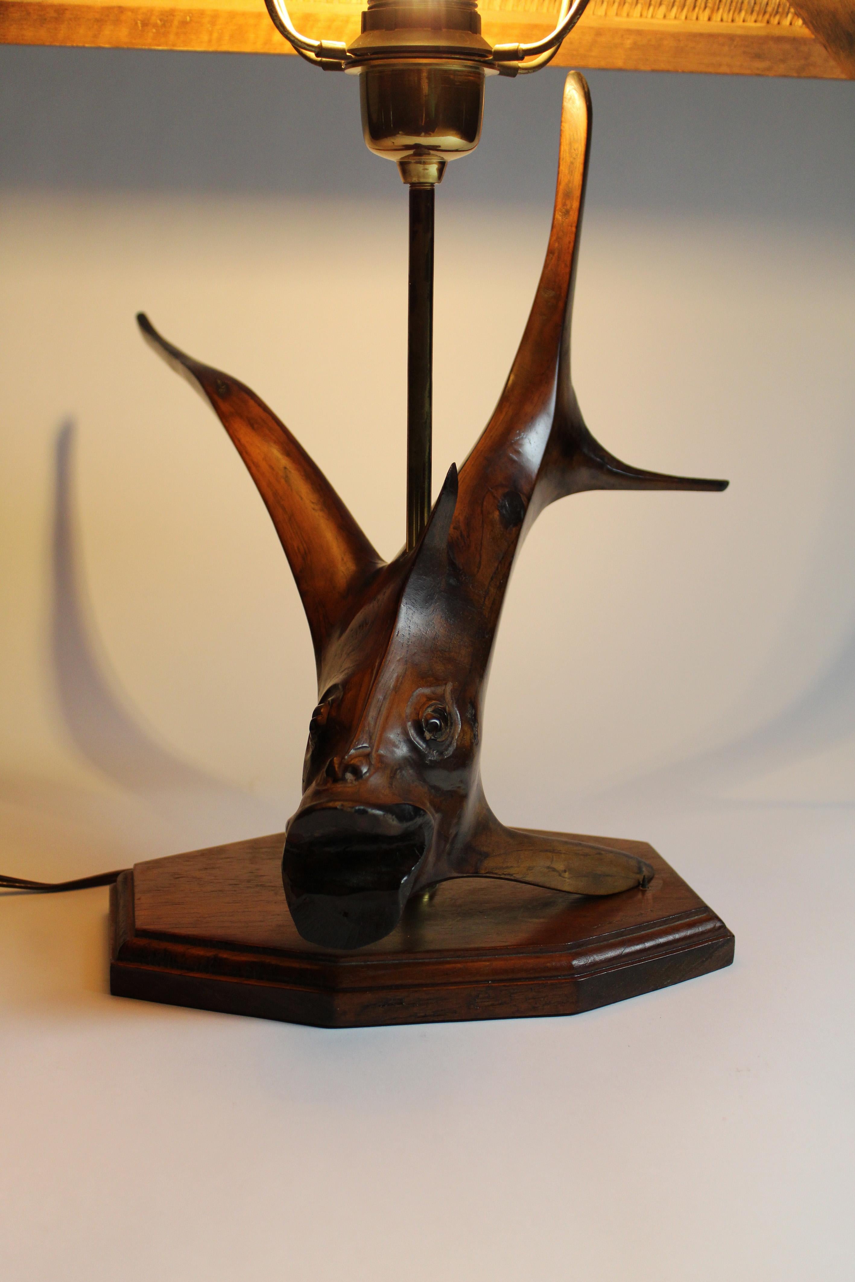 The root wood table lamp with a rattan shade and hardwood flying fish base, designed and signed by Leonard T in 1970 Germany, showcases Japanese-inspired design blended with mid-century European craftsmanship. This piece combines natural materials,