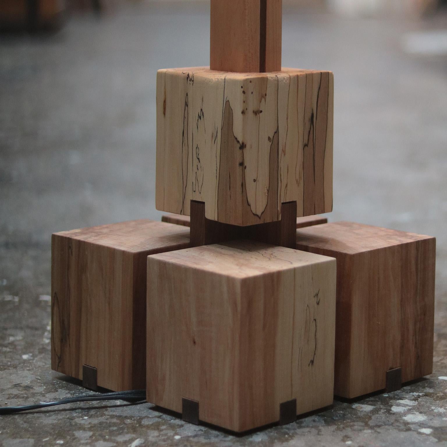 The Rooted floor lamp emerges from the quiet embrace of spalted maple, a material that carries the weight of time within its organic patterns. The base and spine rise with a certain dignity, grounding the piece in a realm where art meets utility.