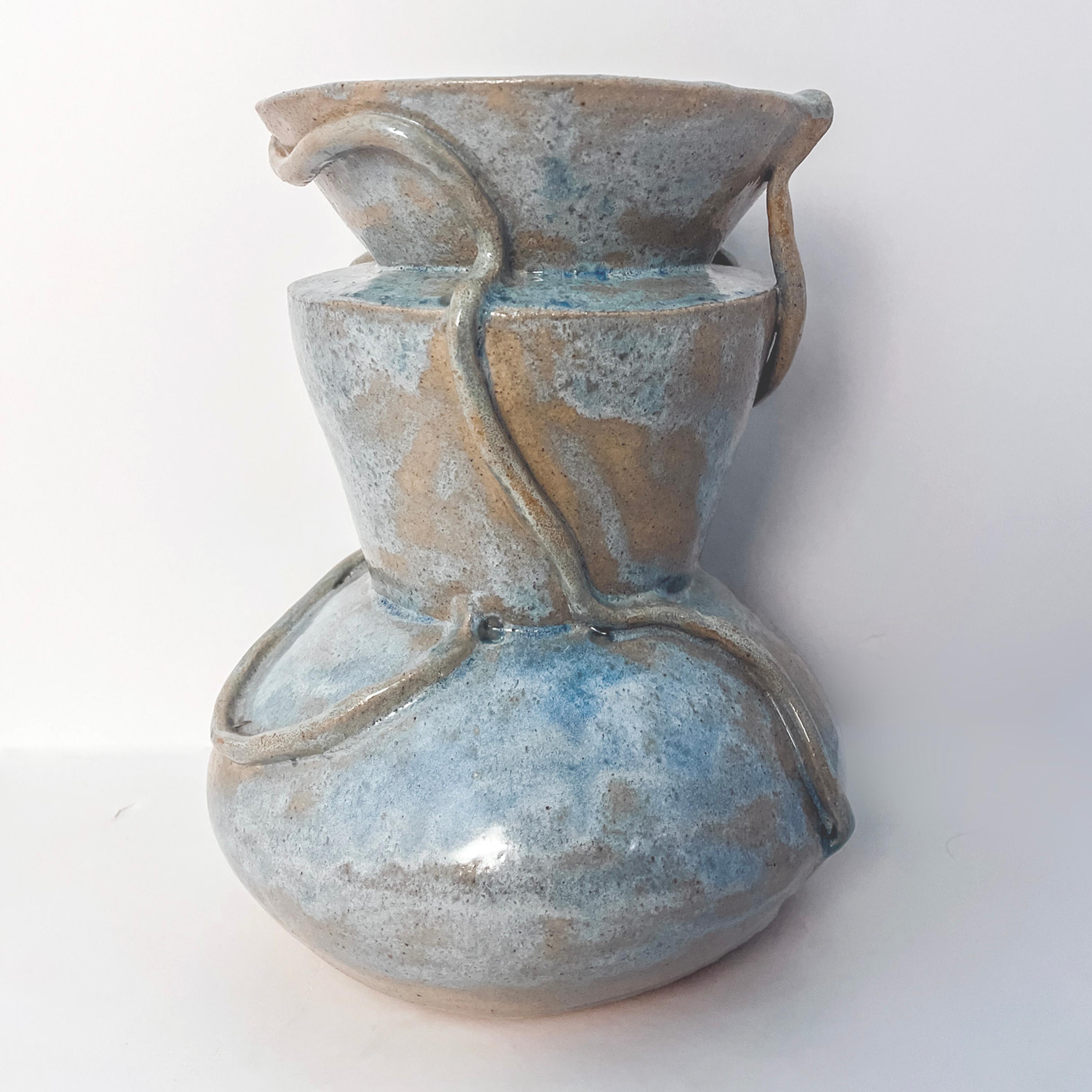 A modern sculptural vase handcrafted in Raku clay and a variegated opal glaze. It It is rich in texture and the glossy blue color against the earthy undertones brings interest to this piece. It is water tight and ready for your floral or plant
