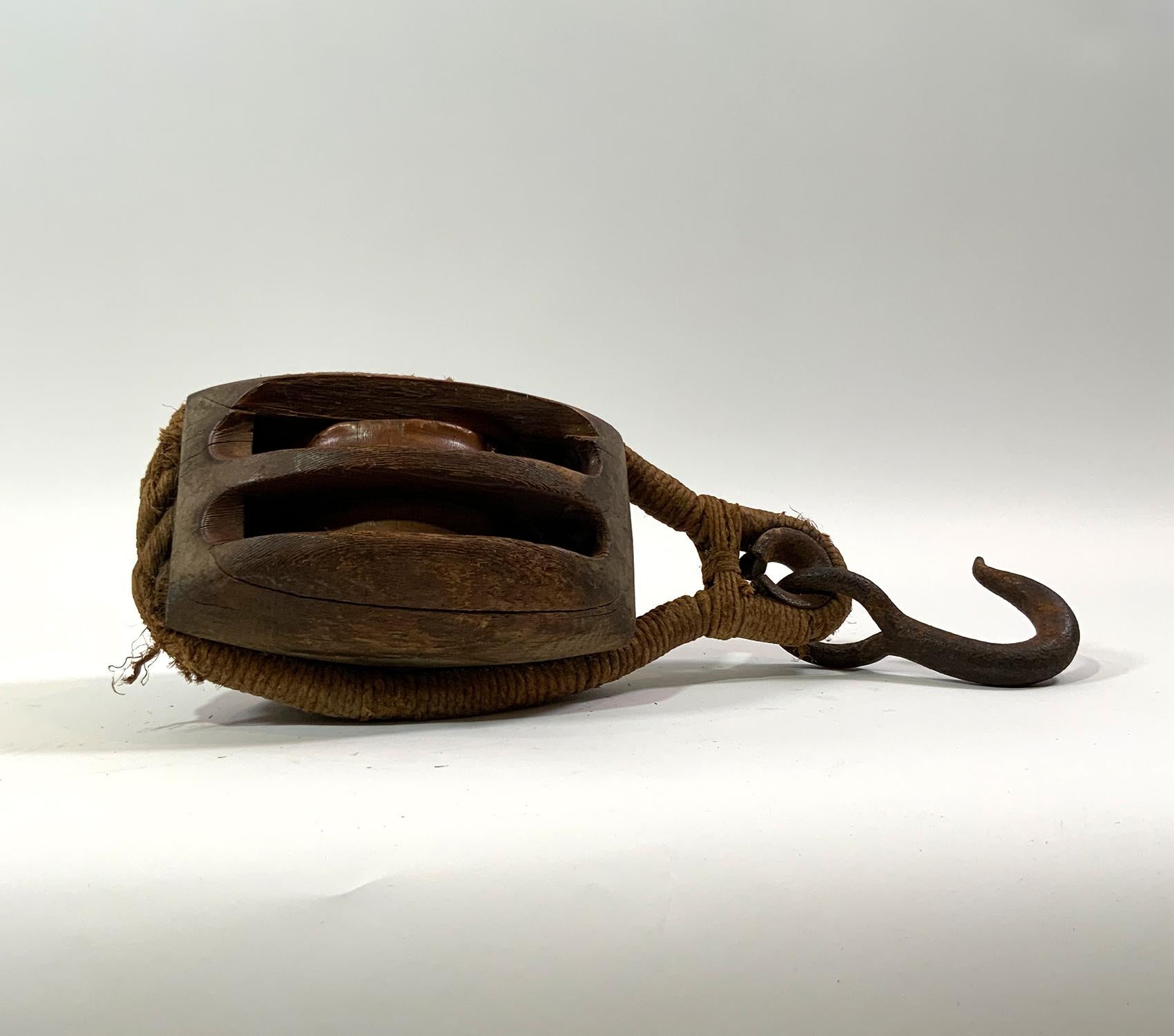 Nineteenth Century wood ships pulley block from a sailing ship, with wood pulleys and rope wrapped hoisting hook. Quality relic. Look at rope work.

Weight: 10 LBS
Overall Dimensions: 16” H x 8” L x 7” D
Made: America
Material: Wood
Date: