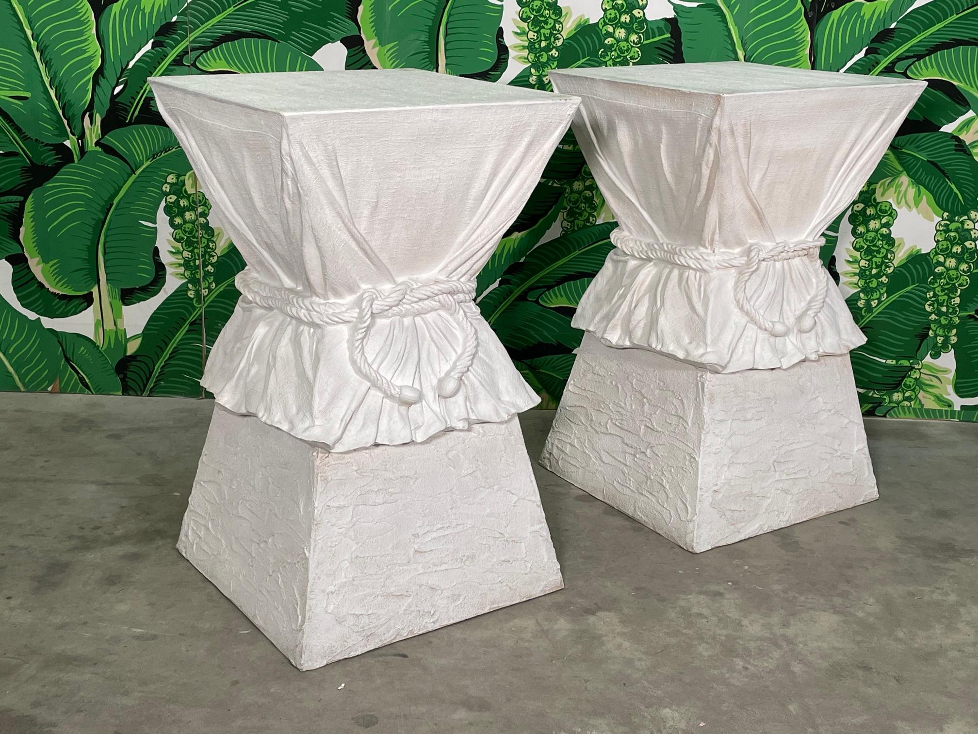 Pair of white dining table pedestals feature a sculptural hourglass shape with faux drapery and rope in the style of John Dickinson or Alberto Pinto. Terracotta structure finished in white gesso. Good condition with imperfections consistent with age