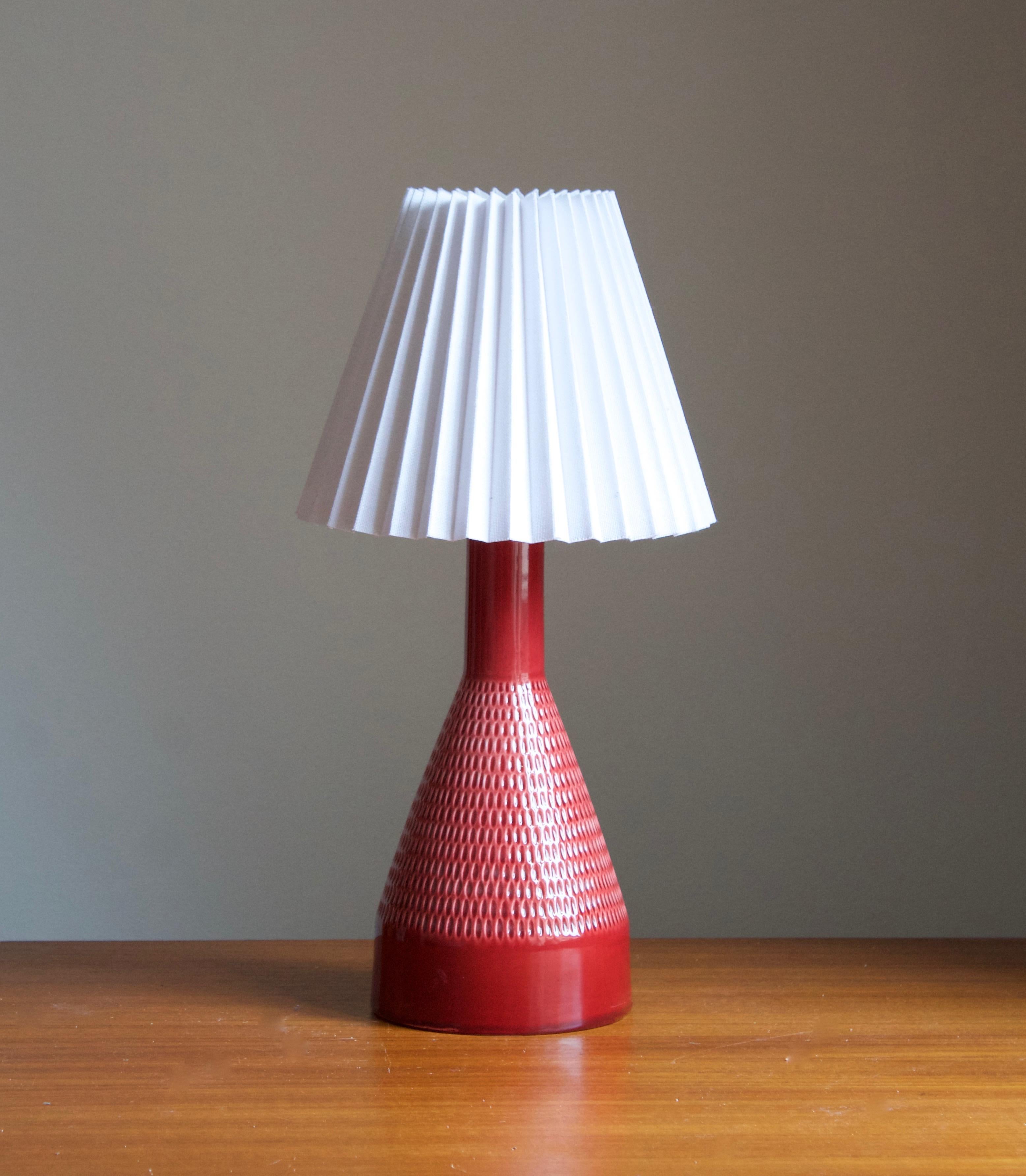 A pair of table lamp produced by Rörstand, Sweden, c. 1960s. Stamped. Base in red glazed ceramic with simple incised ornamentation.

Stated dimensions exclude lampshade, height includes socket. Upon request illustrated lampshade can be included in