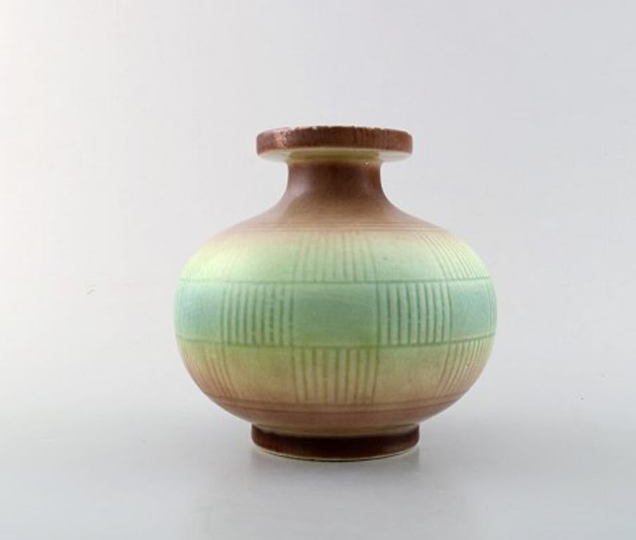 Rörstrand. Round Art Deco vase in stoneware. Geometric pattern and beautiful glaze in light green and brown shades. 1920-1938.
Measures: 14 x 13.5 cm.
In very good condition.
Stamped.
1st factory quality.