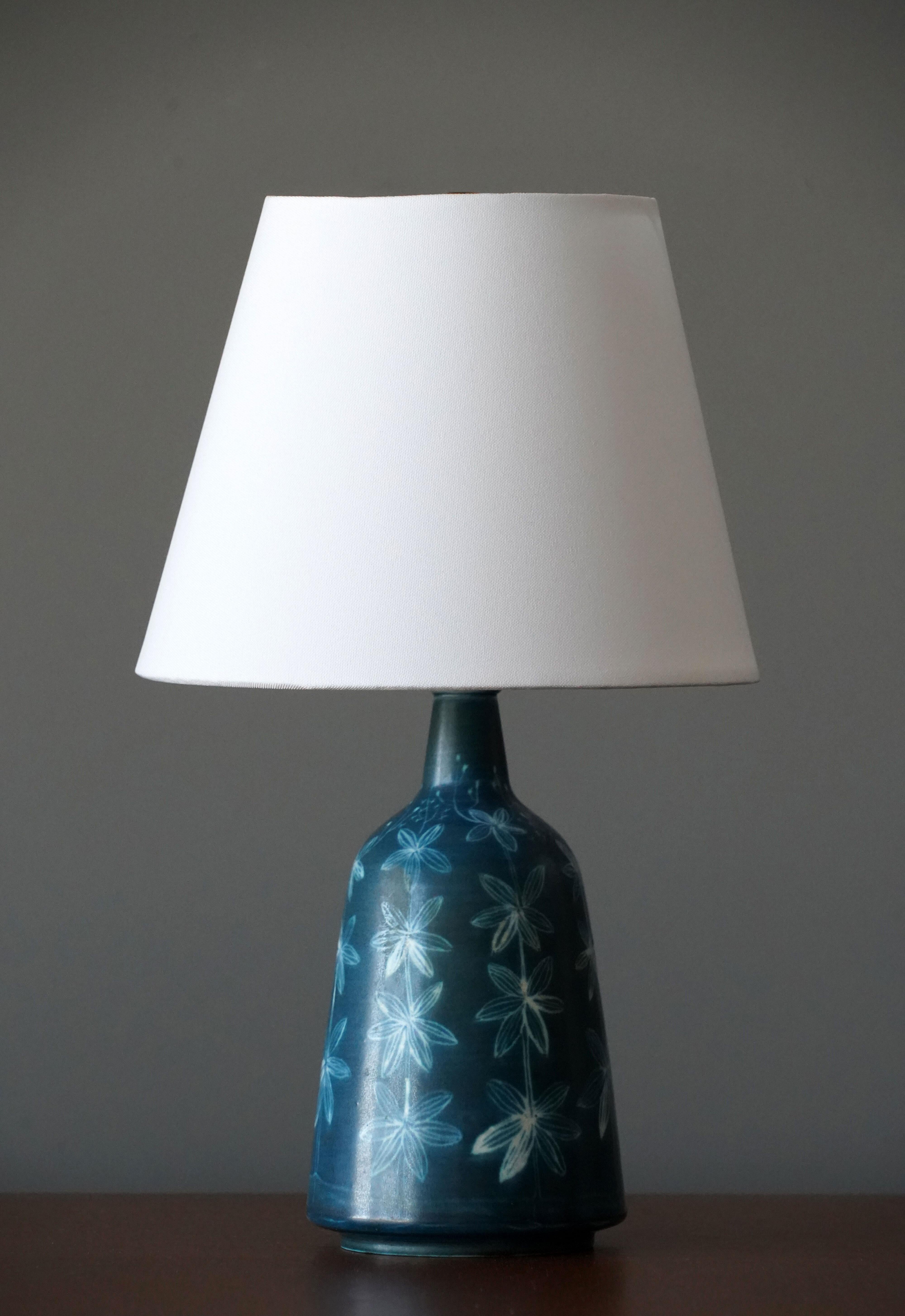 A table lamp produced by Rörstrand. Marked. Features a sculptural form and a highly artistic blue cyantope floral pattern.

Lampshade attached is for illustration, the lamp is offered without a lampshade and stated dimensions are of only the