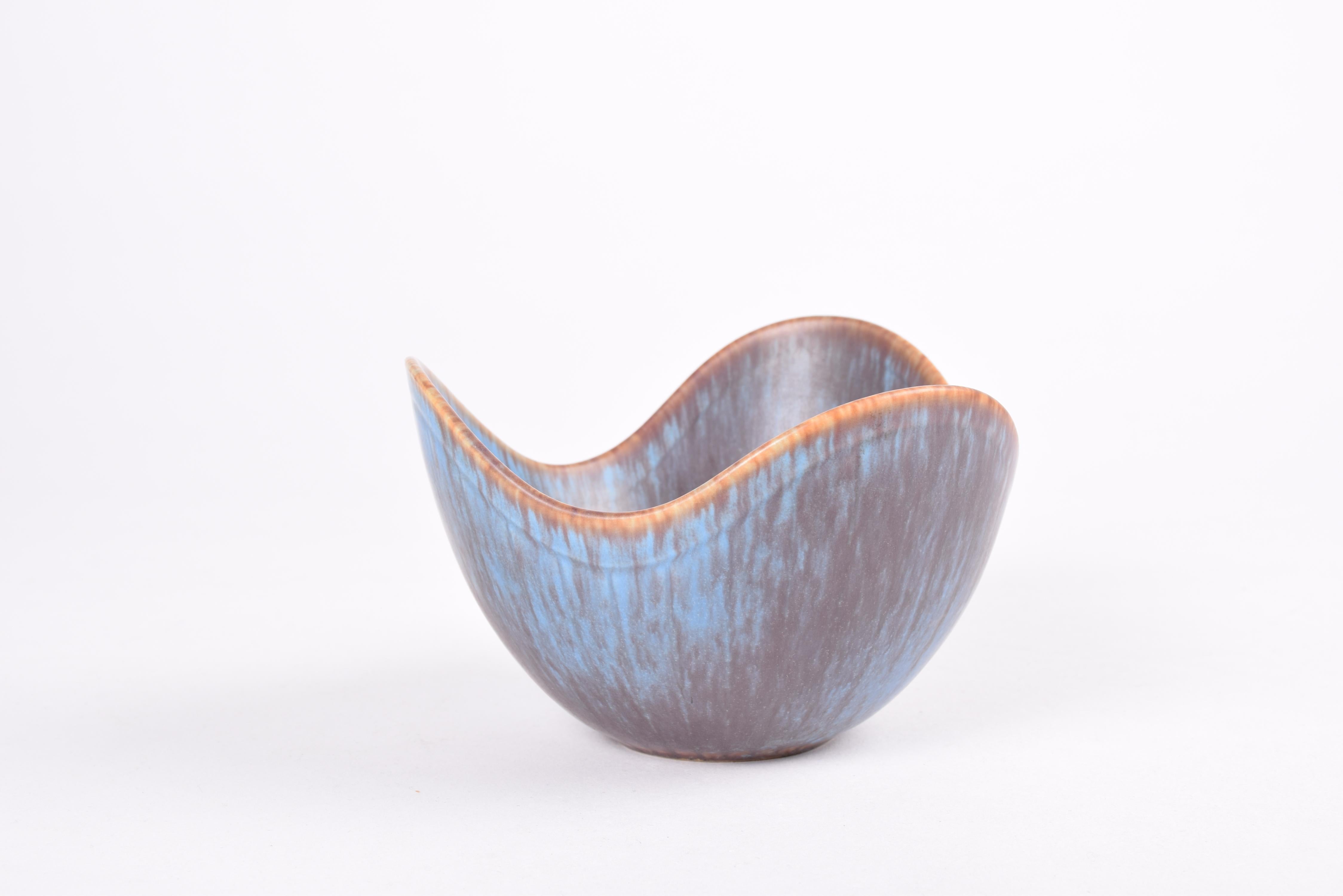 Cuenco vintage de cerámica de Gunnar Nylund para Rörstrand Suecia. Fabricado hacia la década de 1950.

El cuenco es de gres y tiene forma de tres alas. Está decorada con vidriado de color azul, marrón y berenjena. 

Marcado a mano en la parte