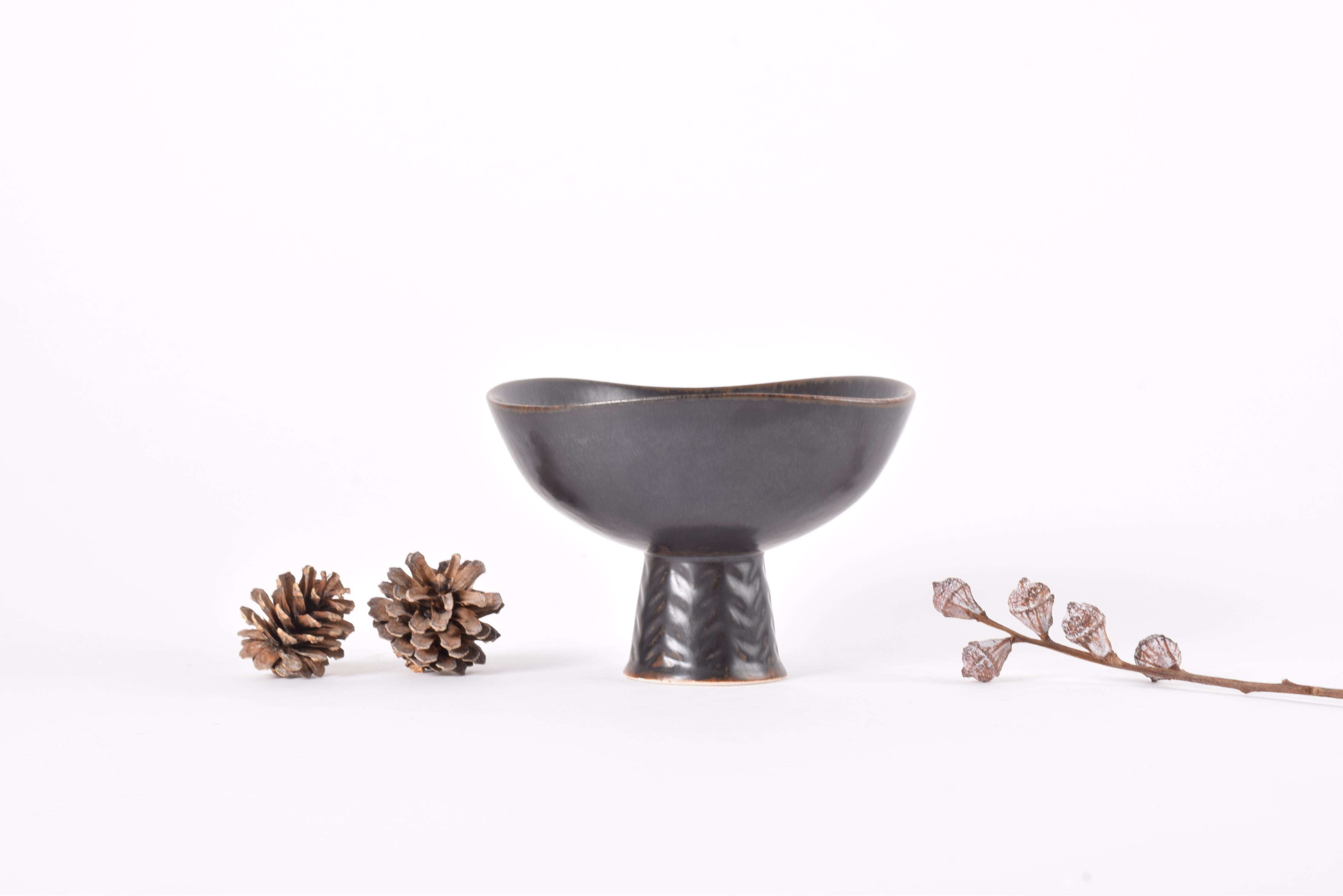 Cuenco con pie vintage del ceramista sueco Carl-Harry Stålhane para Rörstrand Sweden. Fabricado entre los años 1950 y 1960.

El cuenco es de gres, tiene forma ligeramente triangular con paredes onduladas y está decorado con un vidriado marrón oscuro