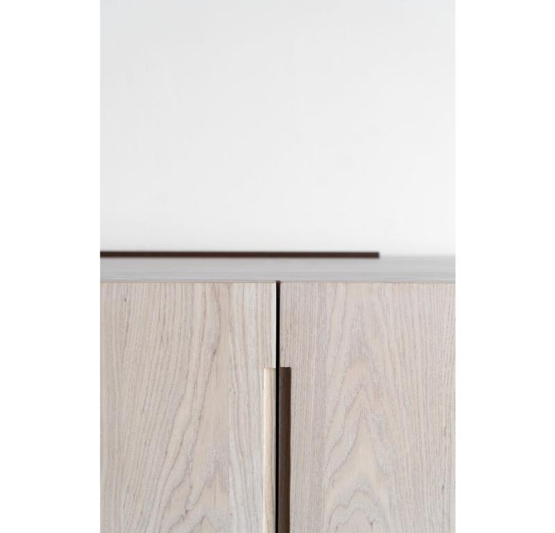 This credenza is custom made in Los Angeles. Industrial steel casing is sheered to size and attached to a substrate. Wood is cut to size and joined to door face. Five doors with soft close hinges. 
ASH + INDUSTRIAL STEEL + BIRCH INTERIOR
PATINA +
