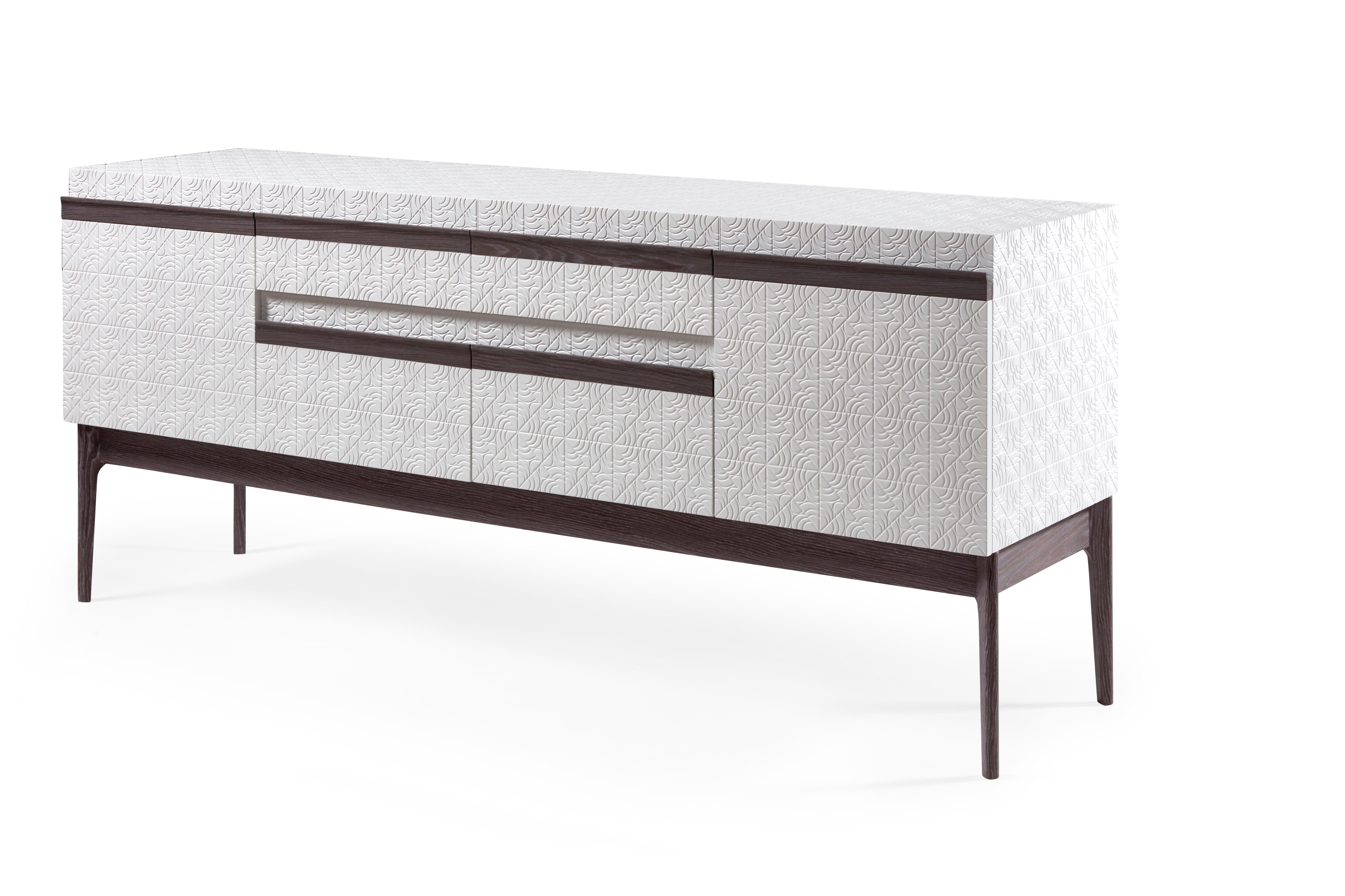 Intricacy and mixed materials collide with the Rosa sideboard. The rose motif, fused with geometric pattern work, is hand carved and lacquered. A contrasting wood detail serves as the cabinet handle for doors and drawers that provide ample dining