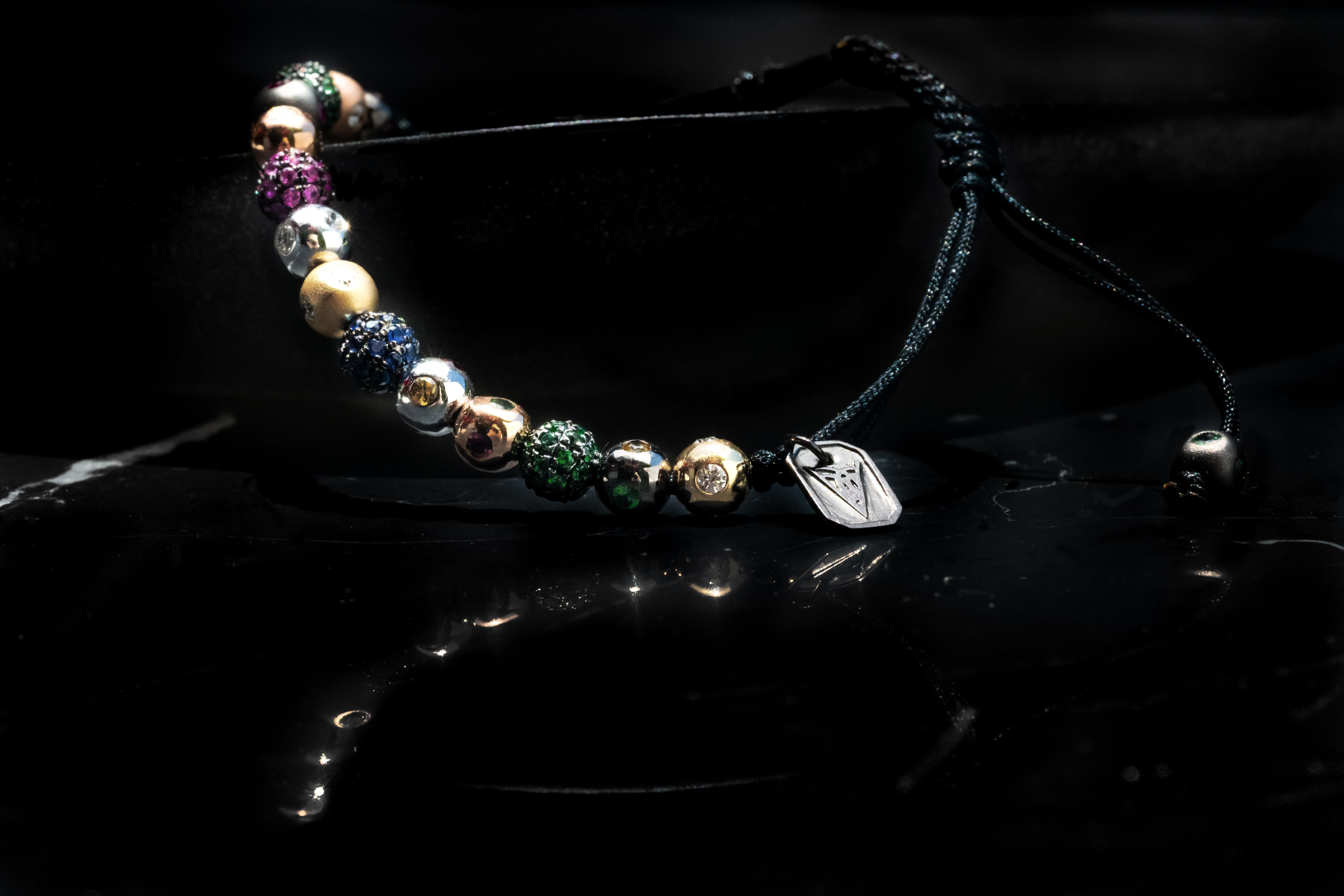 A bracelet made of a medley of fourteen 5mm pavé beads in 18 Karat yellow, white, black and rose Gold, with white Diamonds, Rubies, Tsavorites, blue, orang, yellow and pink Sapphires, in macramé (Ref. B.7)
Carat weight: White Diamond .48 CT / Ruby