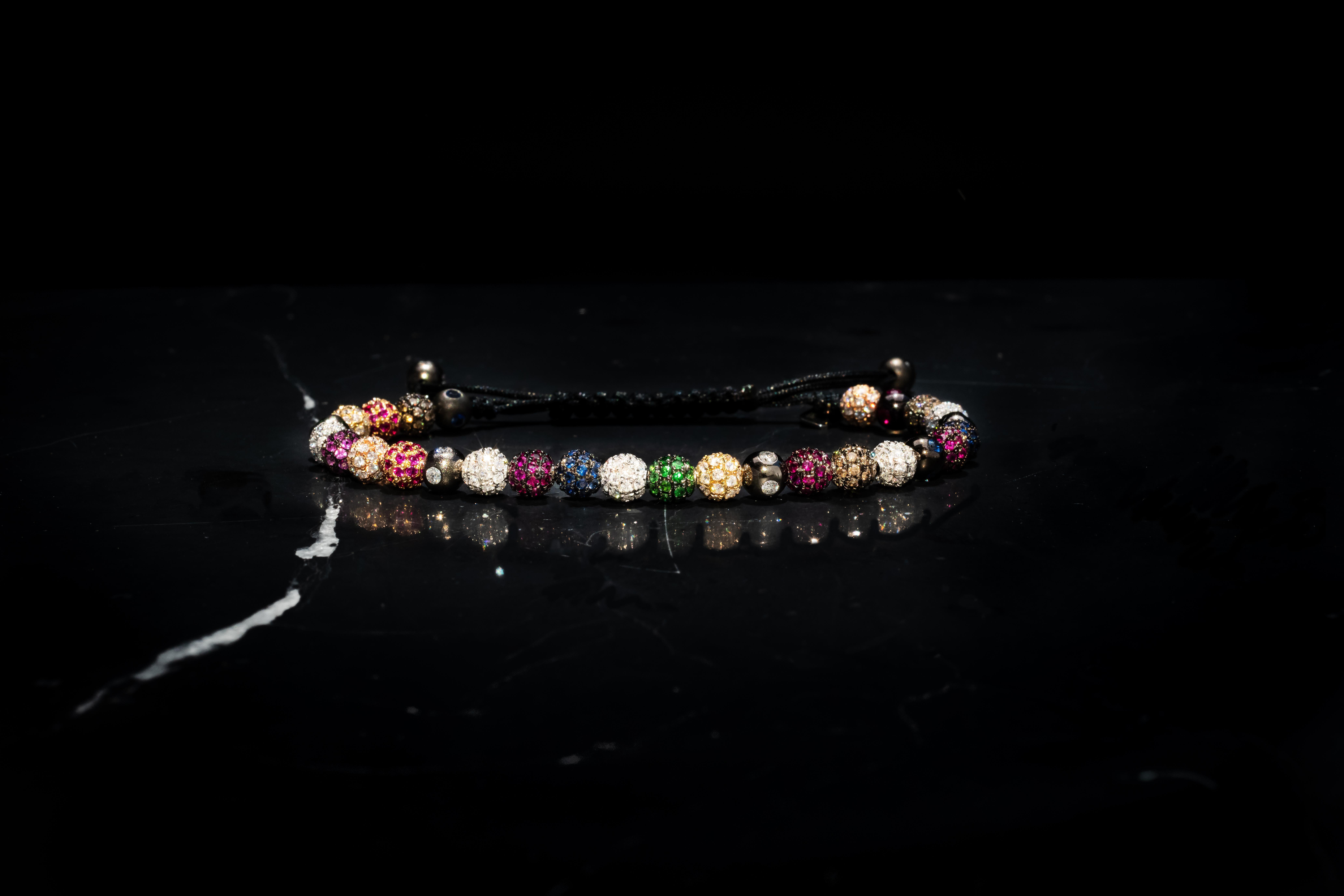 A bracelet made of a medley of twenty-eight 5mm pavé beads in 18 Karat yellow, white, black and rose Gold, with white and brown Diamonds, Rubies, Tsavorites, blue, orange, yellow and pink Sapphires, in macramé (Ref. B.6)
Carat weight: White Diamond