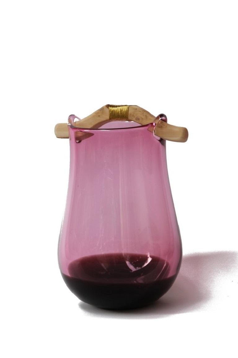 Vase Heiki en rose et topaze, Pia Wüstenberg
Dimensions : D 20-22 x H 32-40
MATERIALES : verre, bois, fil métallique.
Disponible dans d'autres couleurs.

Inspiré d'une simple réparation d'un vieux manche de louche de sauna, fixé avec du fil de fer