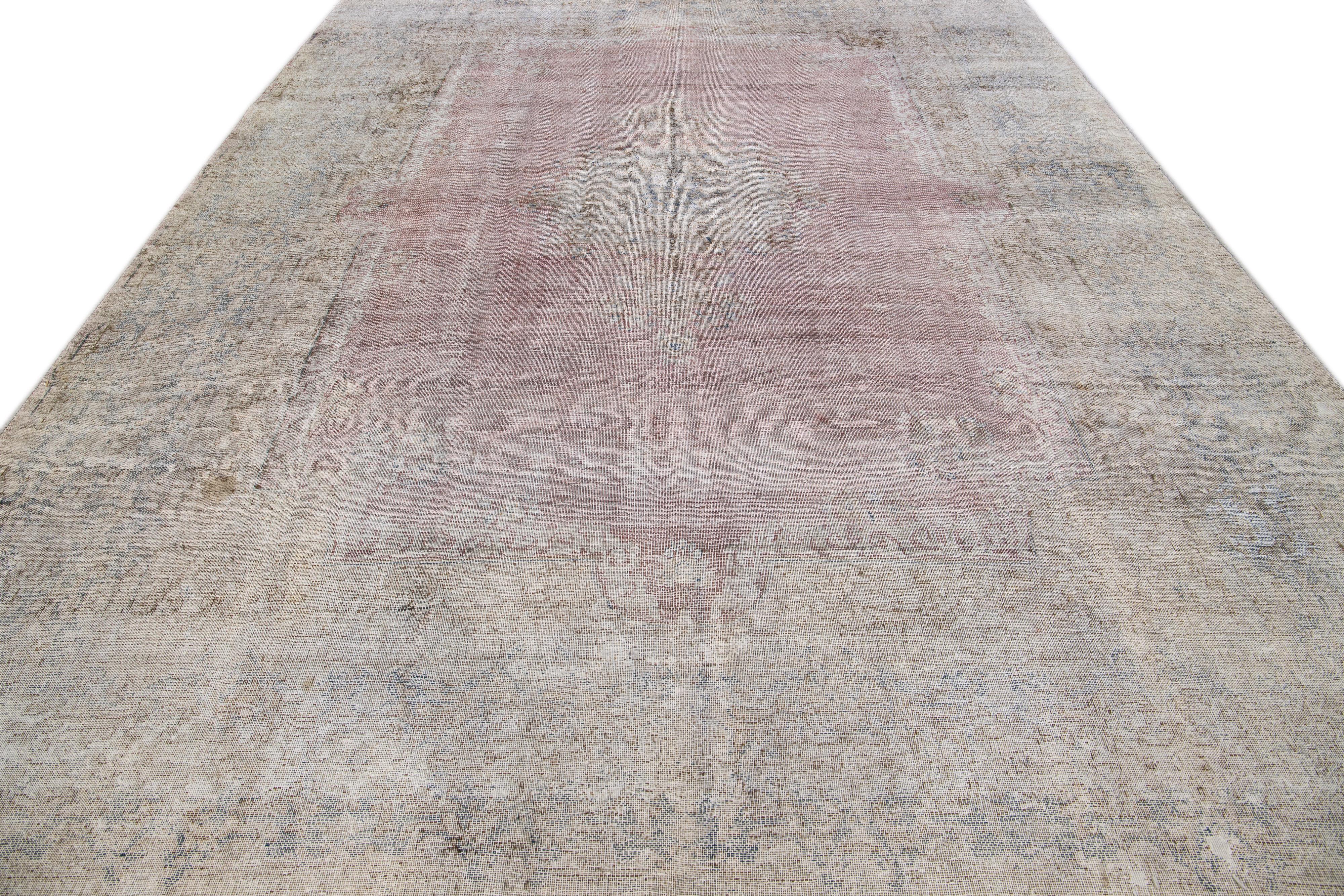 Beautiful antique Tabriz hand-knotted wool rug with a rose color field. This Persian rug has a blue frame and beige accents in a gorgeous all-over medallion design.

This rug measures: 9'9