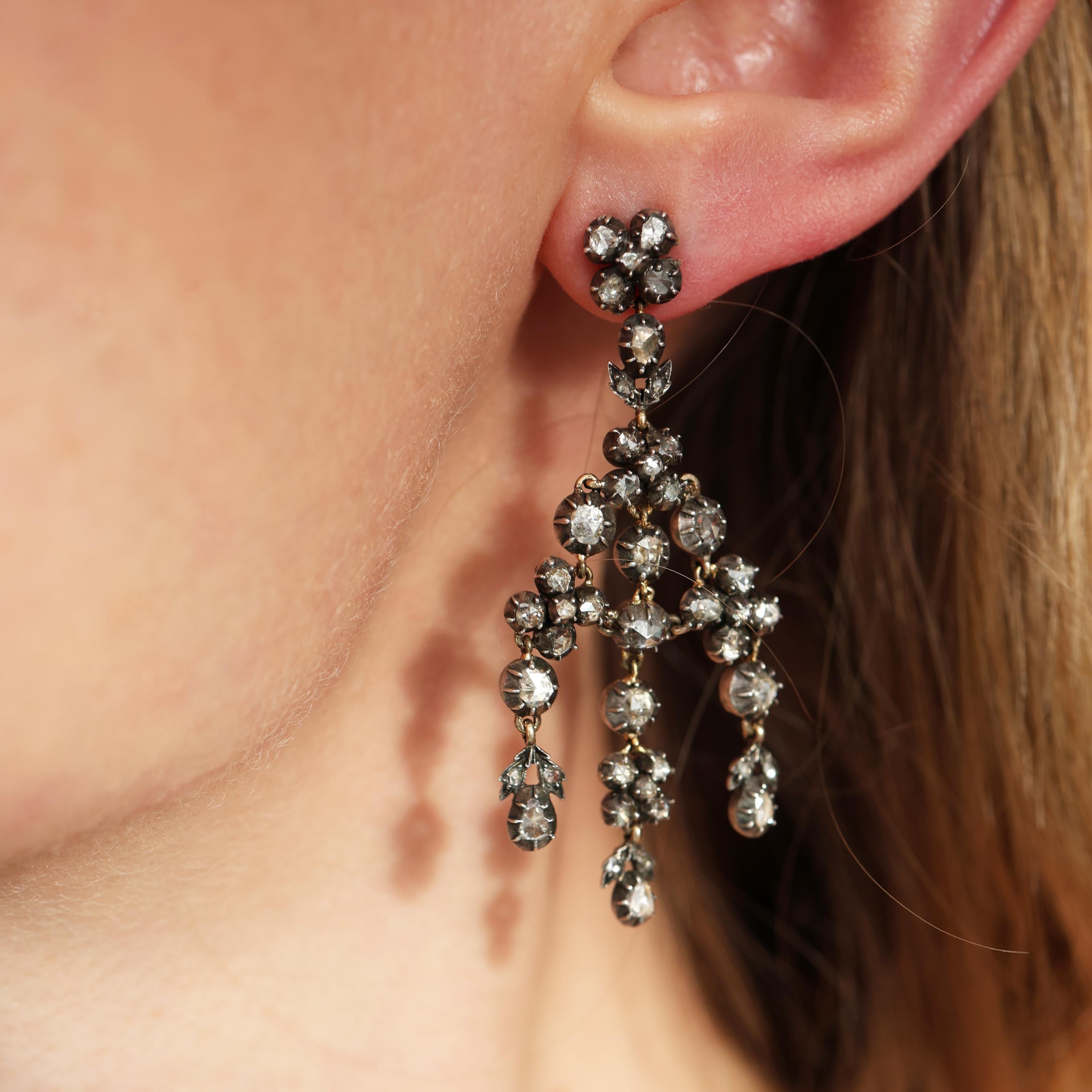 Une paire de boucles d'oreilles girandoles en diamant taillé en rose et en argent sur or, avec des diamants taillés en rose, montés dans des montures individuelles et des groupes de cinq diamants, avec des pendentifs en diamant en forme de goutte,