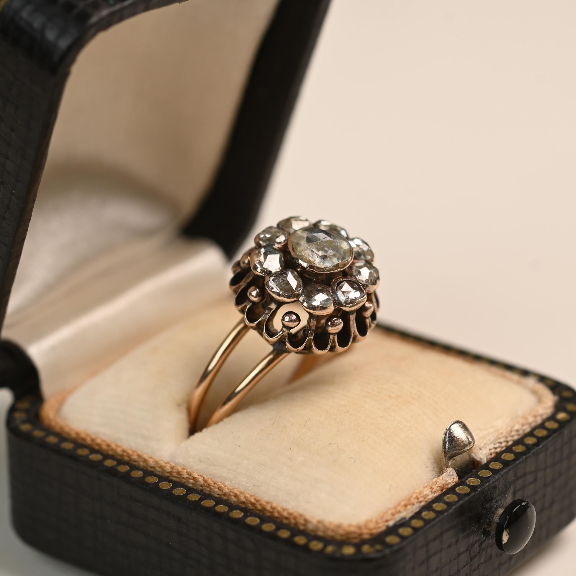 This exquisite Georgian era ring, circa 1810, features a captivating cluster of rose cut diamonds arranged in a charming floral domed design. The openwork detailing surrounding the diamonds enhances the light play and vintage allure of the piece. A