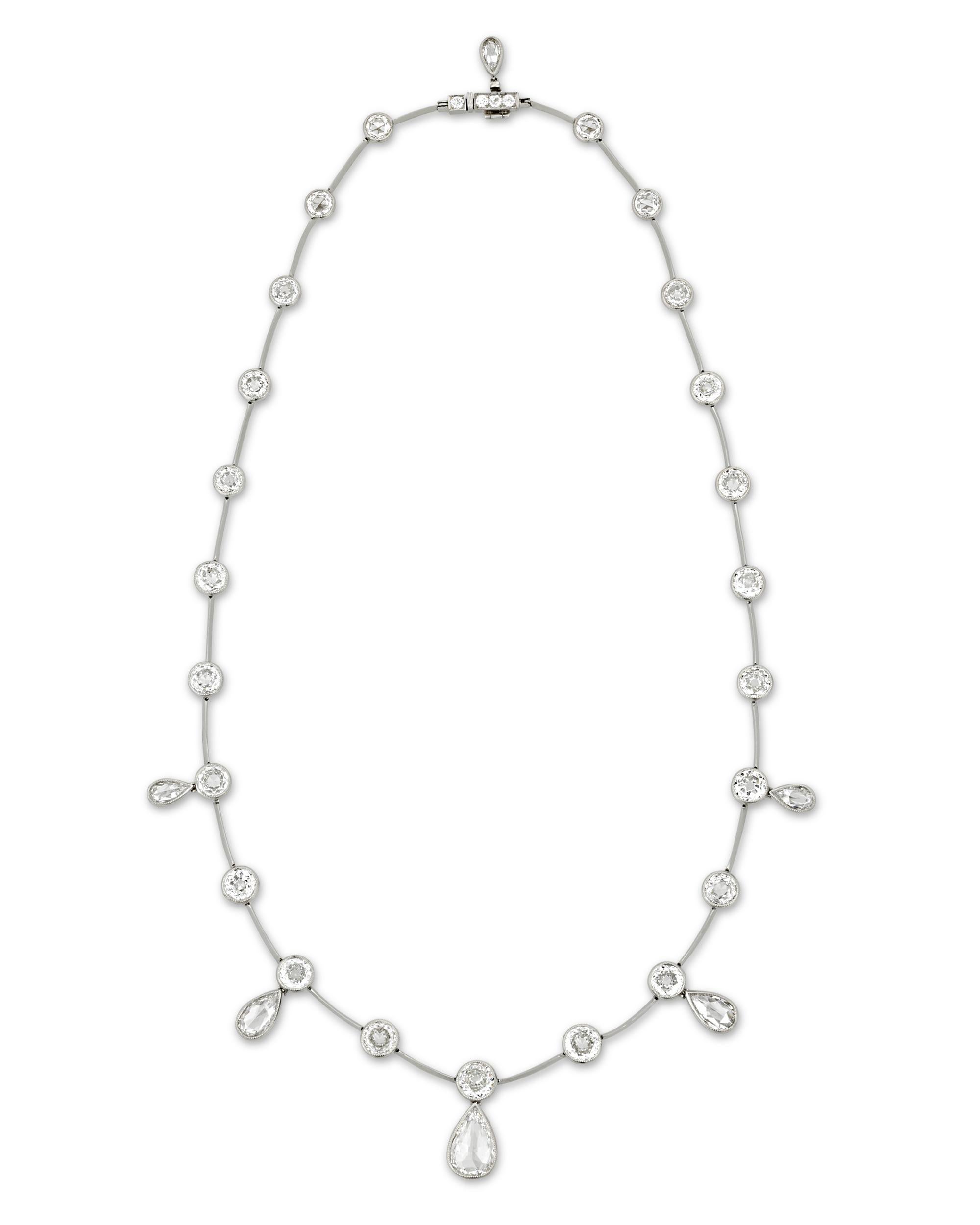 This sensational necklace showcases a design illuminated by a marvelous array of rose-cut diamonds weighing a total of 14.73 carats. Six pear-shaped white diamonds dangle from a sleek chain lined with bezel-set round diamonds. Set in platinum and