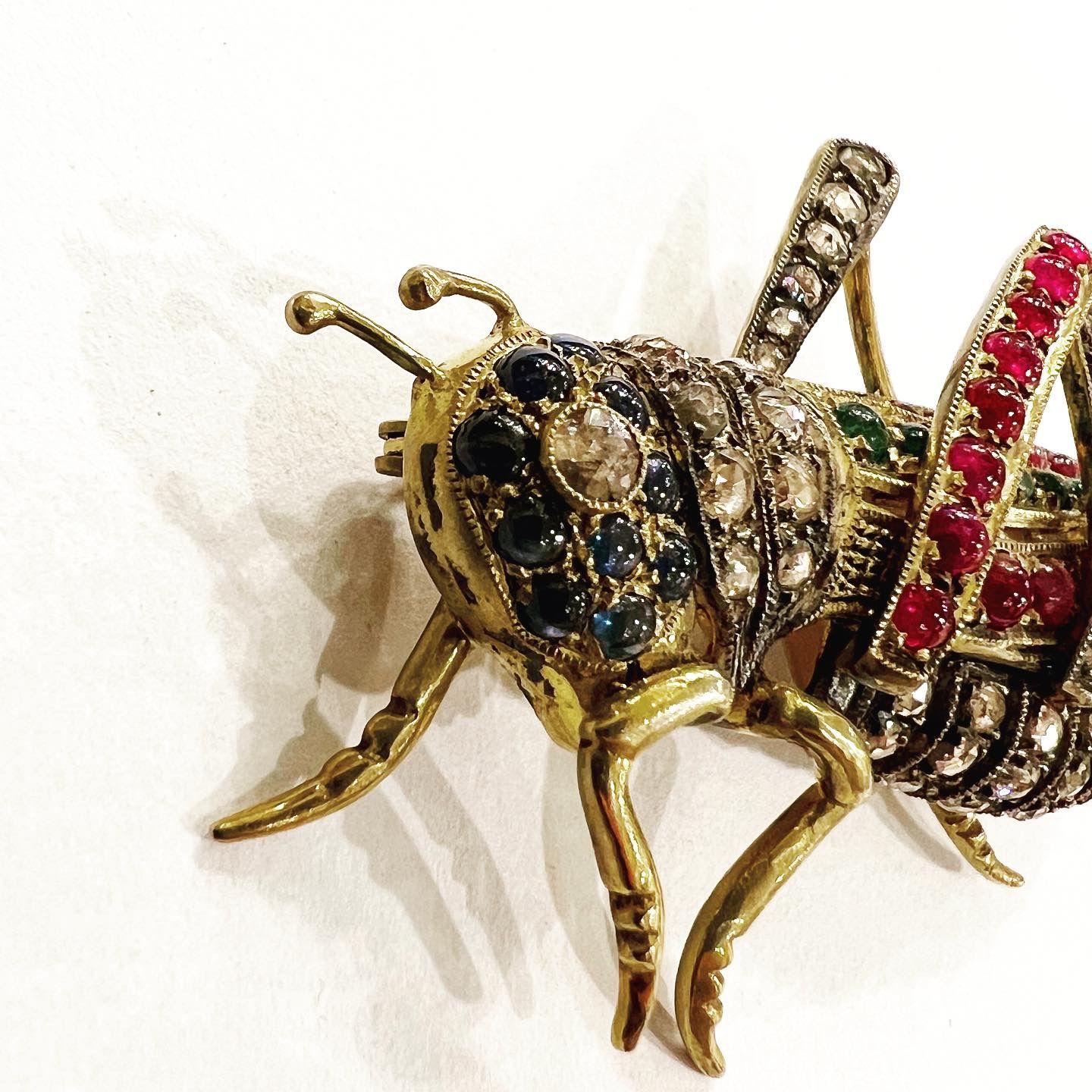 Grasshopper or Cricket form brooch-pendant, set with rose cut diamonds and cabochon sapphires, emeralds and rubys.
Total aproximated diamonds weight: 2.25 carats.
Total aproximated rubys weight: 2.2 carats.
Total aproximated sapphires weight: 0.85