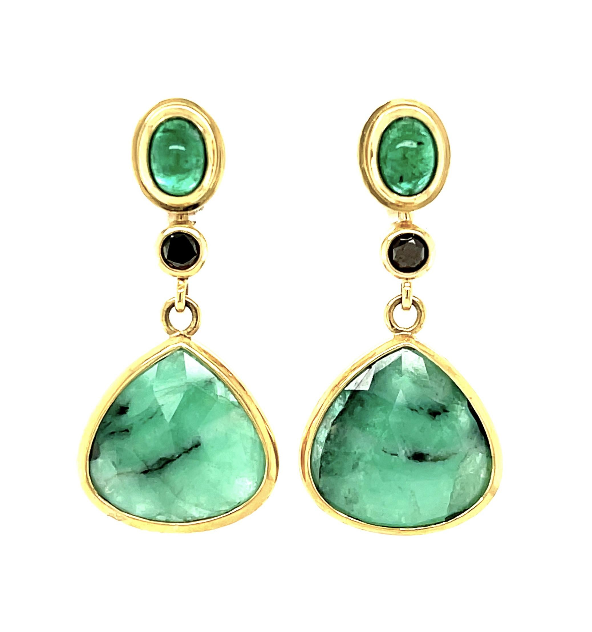 These fun emerald earrings are sure to be your new favorites! The bright green, pear shaped drops have been faceted to reflect light and show off their gorgeous hue. Matching oval cabochons and dramatic black diamonds highlight the striking color