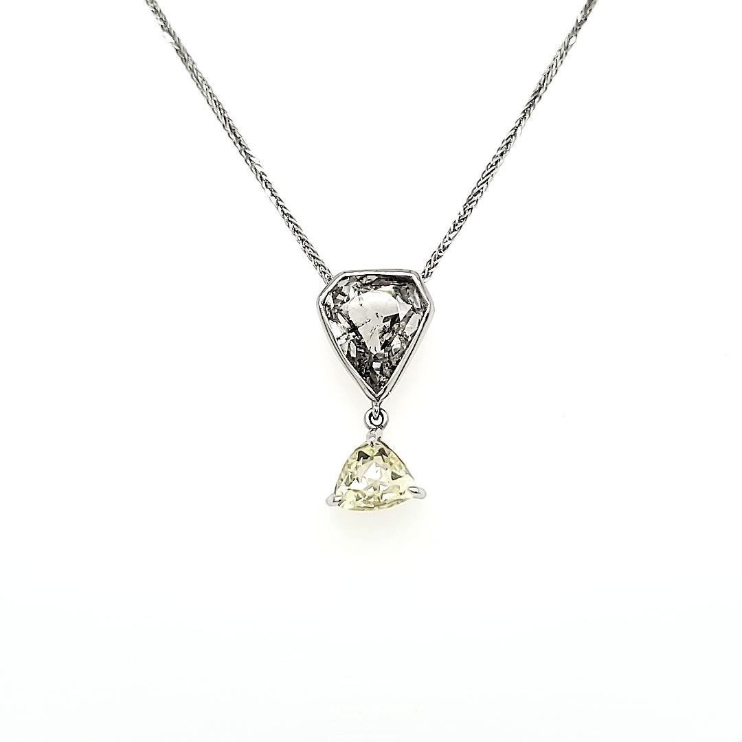 At the heart of this exquisite piece lies the dazzling Rose Cut Diamond Pear, a centerpiece of sheer radiance boasting 1.84 carats. 

Connected to this elegant pear is the enchanting Diamond Triangle, totaling 1.09 carats, delicately dangling and
