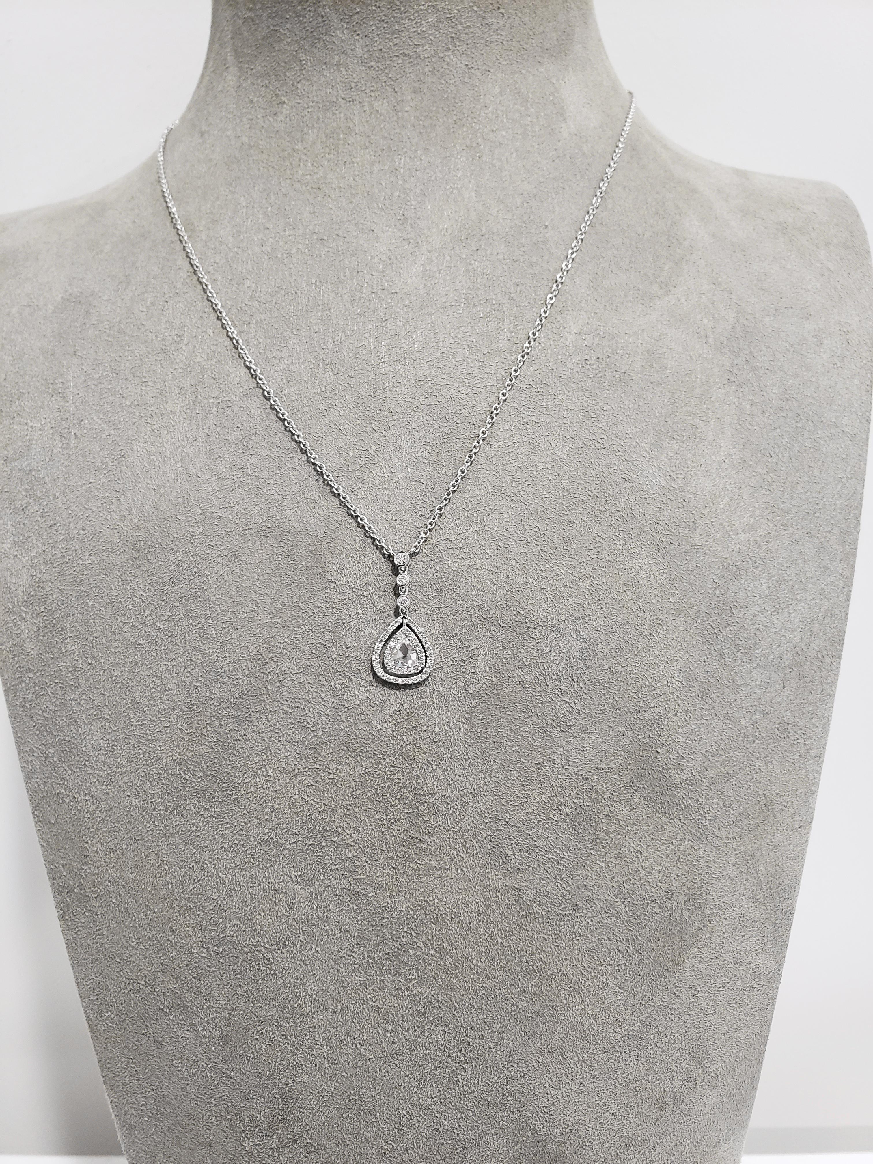 Showcasing a single 0.40 carat rose cut diamond surrounded by two rows of round diamonds in an open-work design. Suspended on 3 round diamonds, bezel set in 18 karat white gold. Attached to a 14 karat white gold chain that is adjustable to 16 and 18