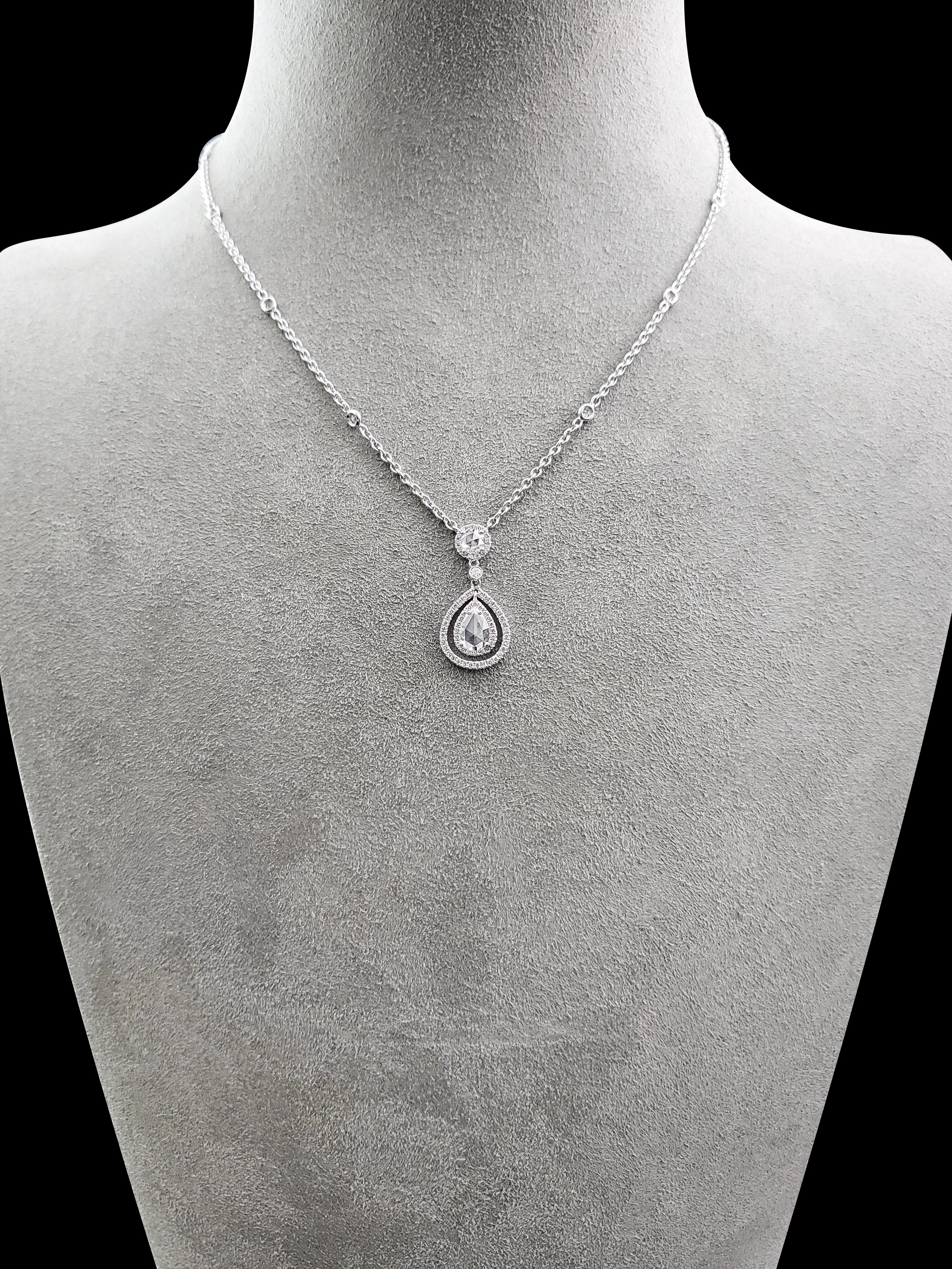 A unique drop necklace showcasing a pear shape rose cut diamond weighing 0.55 carats total. The center diamond is elegantly framed in a diamond encrusted double halo setting that suspends on a 0.21 carat rose cut round diamond. Attached on an 18