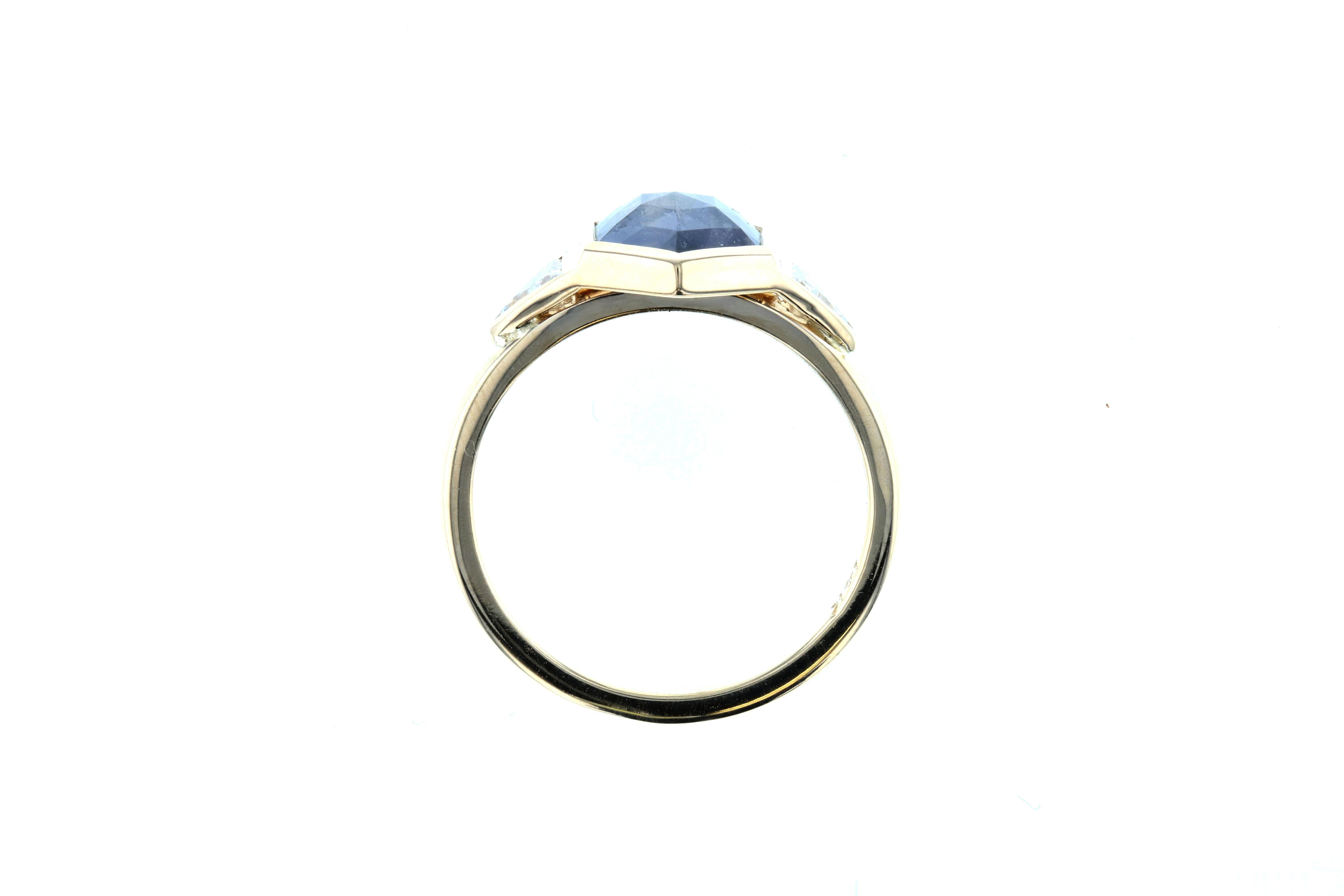 This salt and pepper diamond engagement ring features a rose cut salt and pepper diamond surrounded by two white diamond trillion side stones. Set in yellow gold with a bezel setting for a vintage look on a modern trend, this salt and pepper diamond