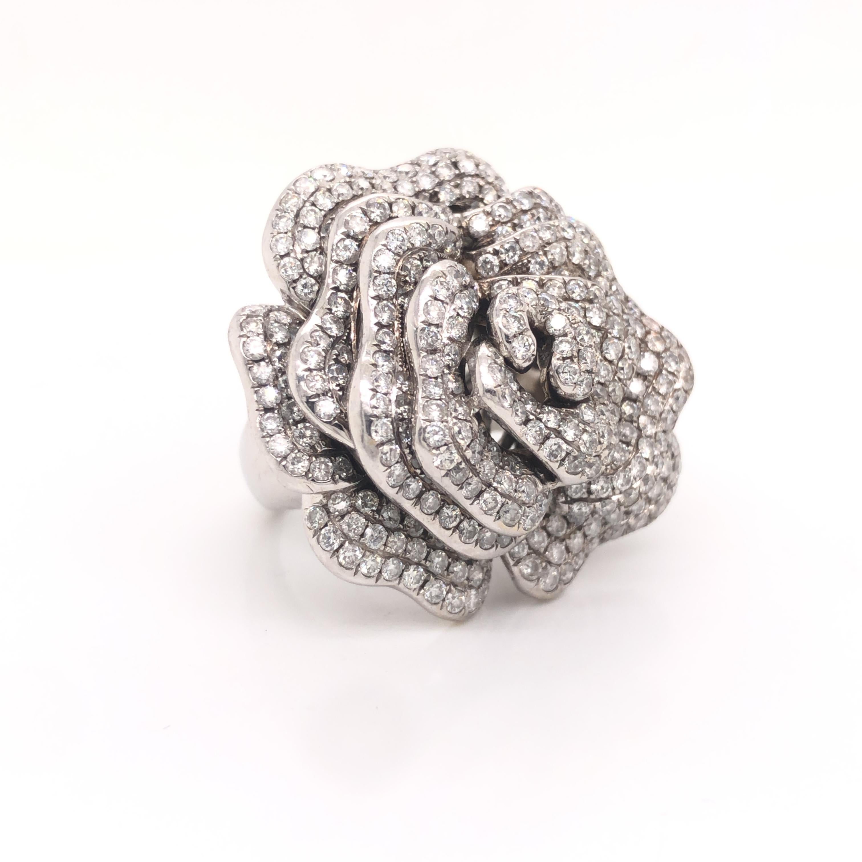 Gorgeous creation crafted in 18k white gold. This beautiful cocktail ring is crafted in the style of a rose flower with diamonds set throughout. The design is crafted by masters of their time, as different levels of white gold come off the design