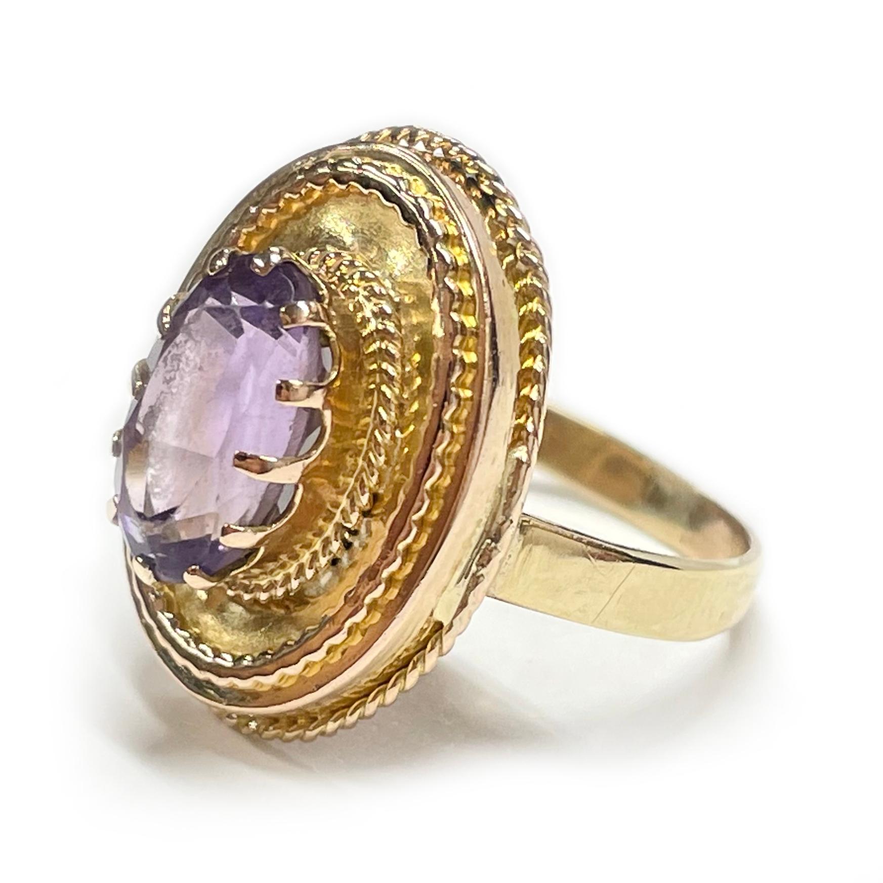 14 Karat Rose Gold Amethyst Cocktail Ring. The ring features an oval-cut 8 x 10mm Amethyst with textured wire gold details. The medium color gemstone is prong-set with twelve prongs. The Amethyst has light scuffs but is in good vintage condition.