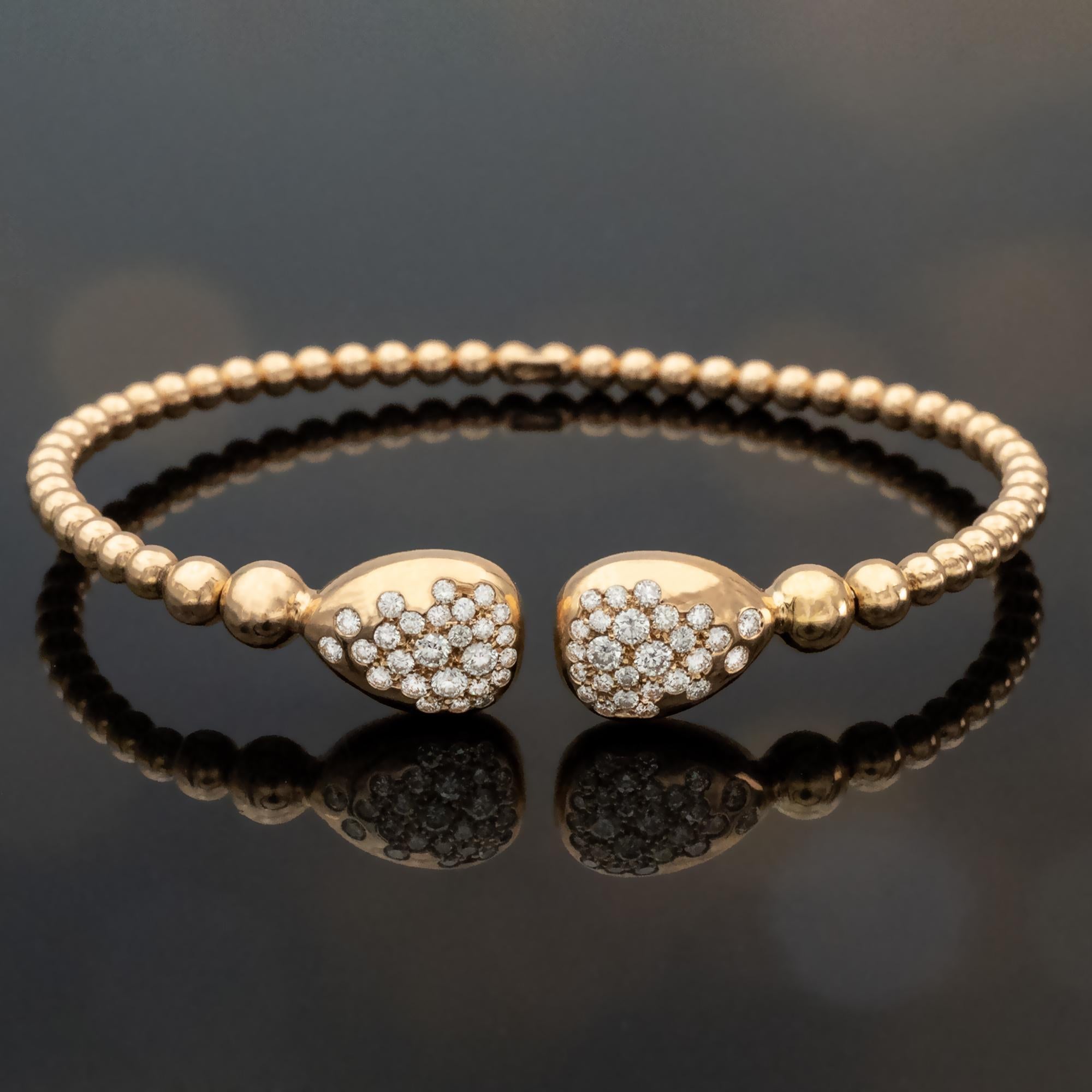Esta pulsera brazalete flexible, ofrecida por Claris-A, está elaborada en cálido oro rosa y presenta una fina estructura de cuentas articuladas que envuelve suavemente la muñeca. Su construcción fluida confiere a la pieza un movimiento delicado, que