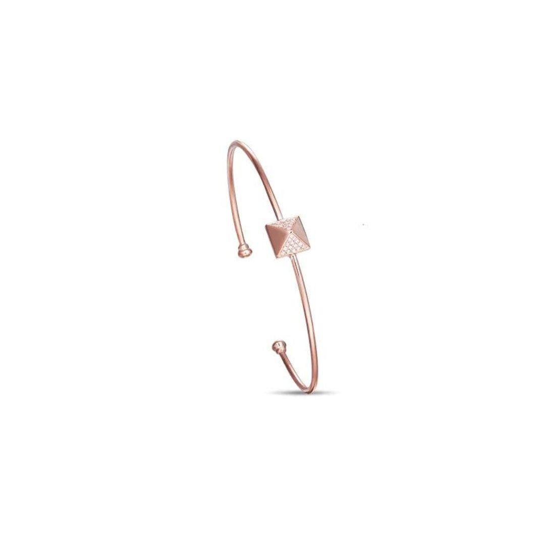 Stylish 14k rose gold bangle. Bangle features a trendy pyramid element with pave set round brilliant diamonds. Perfect to wear on its own or stacked with other bangles. Diamonds are H-I color, SI clarity, total carat weight 0.13 ctw. One size fits