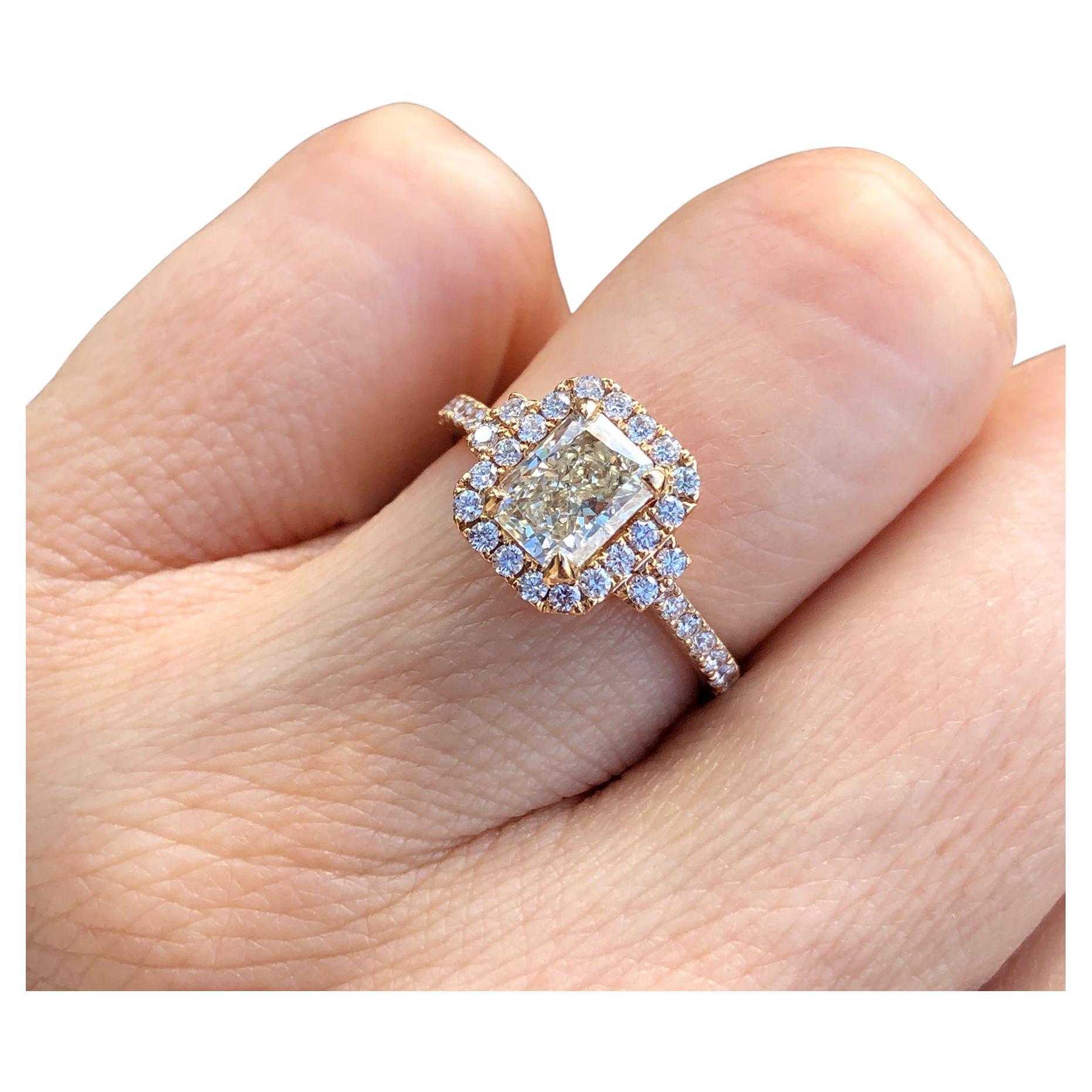 18K rose gold diamond engagement ring with radiant cut, pale yellow diamond on halo diamond mounting.

Features
18k rose gold
1.22 carat radiant cut, pale yellow diamond 
.40 carat total weight in white diamonds on the mounting
Ring size 7. Can be