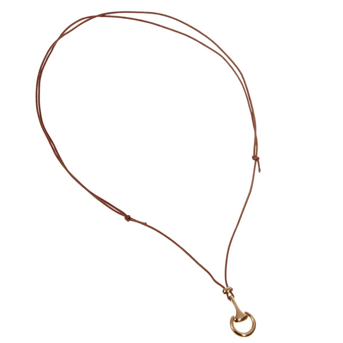 Un collier fin présentant un motif de mors en or rose 18k suspendu par un cordon en cuir brun réglable jusqu'à 30