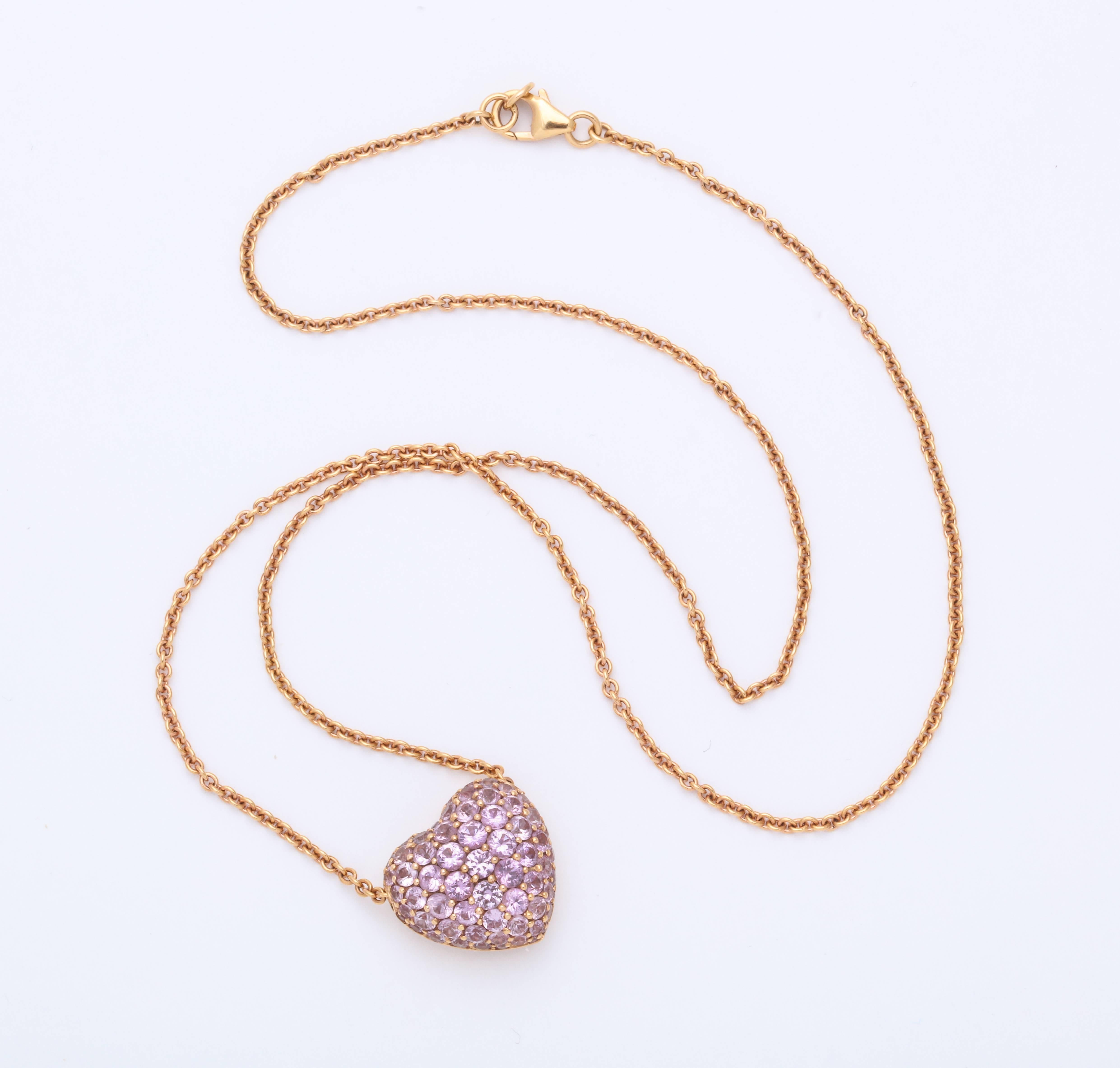 Beautiful and classic domed 18 karat role gold heart shaped pendant decorated entirely with pave'-set round diamond-cut pink sapphires weighing 3.28 carats. The pendant floats freely on the concealed 18 karat rose gold chain.
