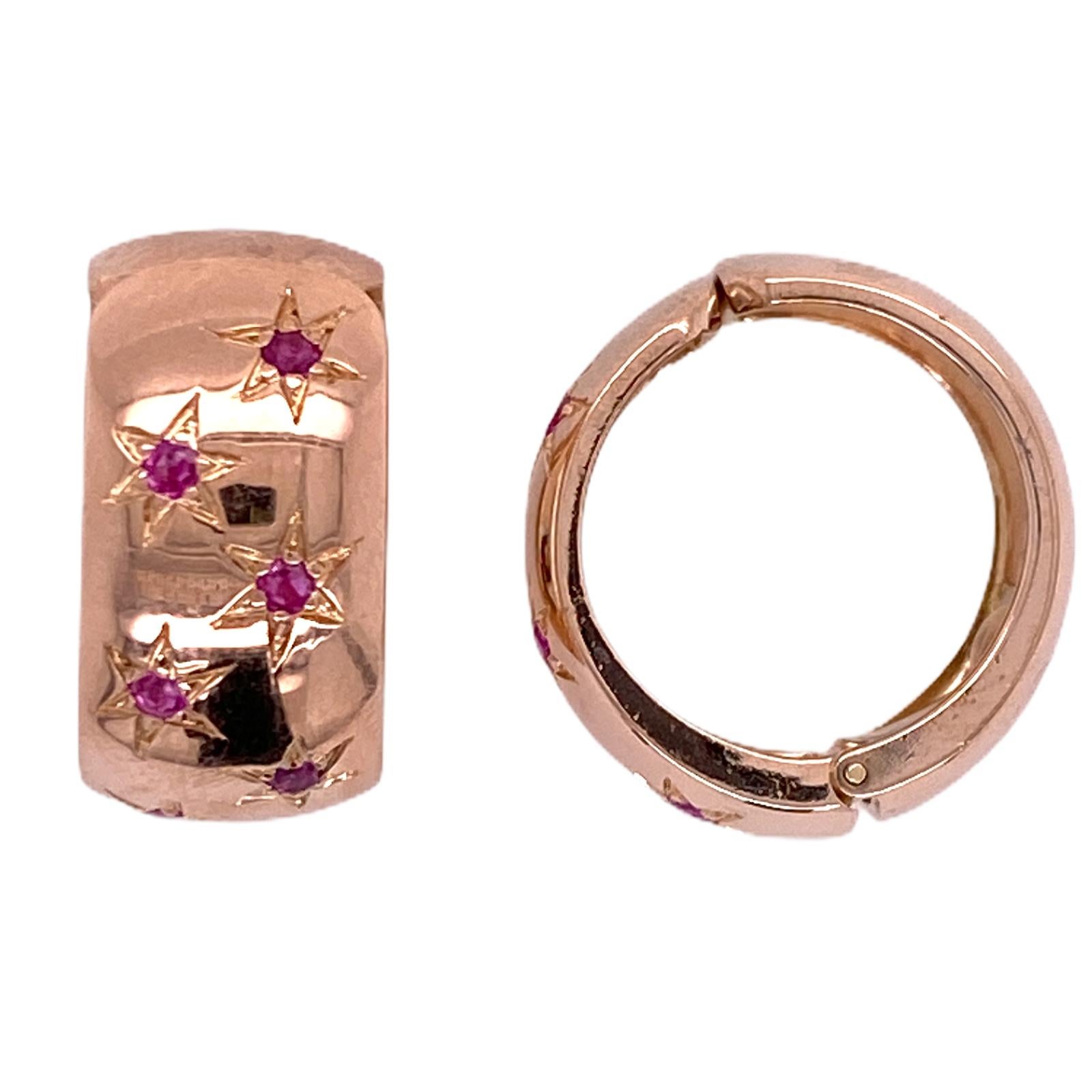 Easy to wear ruby rose gold huggie hoops fashioned in 14 karat rose gold. These comfortable hoops clip onto the ear no post. The earrings are set with ruby gemstones set inside etched stars. The earrings measure 20 x 20 mm. 