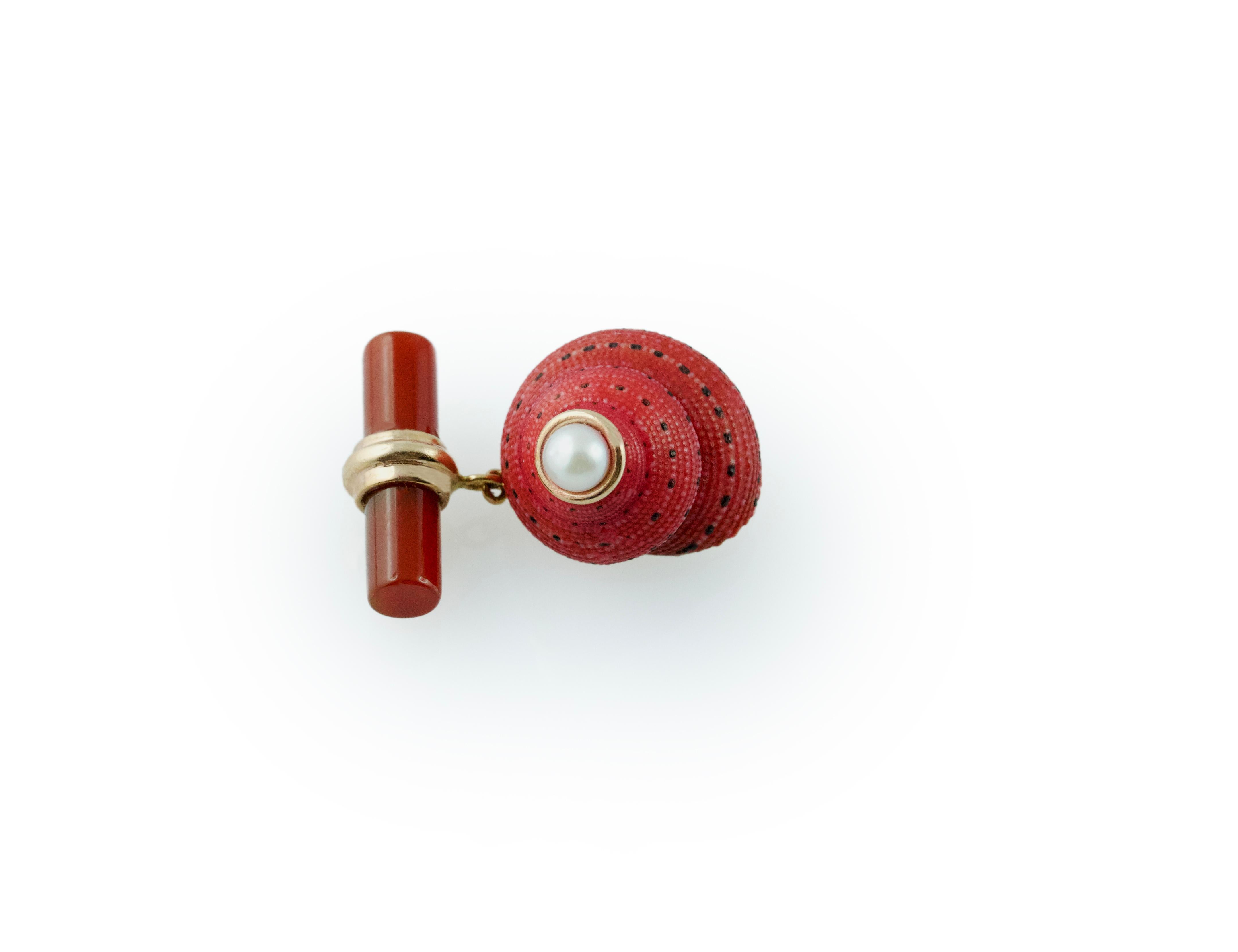 The striking red shade and natural texture of the  shell, adorned with a pearl at the top, is the protagonist of the front face of this elegant pair of cufflinks, which also features a cylindrical toggle in carnelian stone, whose red matches the one