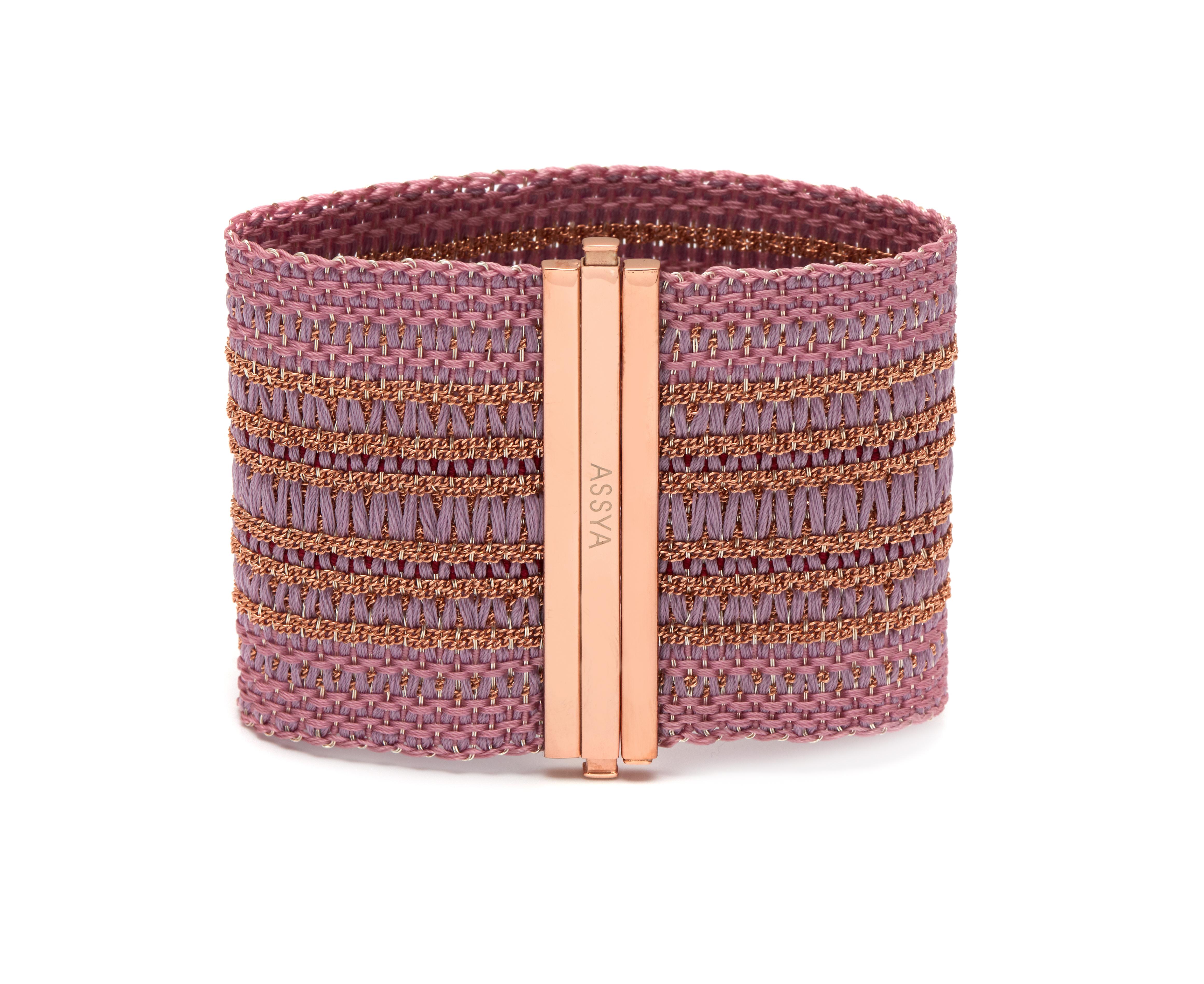 ASSYA London s exquisite Woven collection is handcrafted on an Italian loom using an ancient Florentine technique. The bracelet is cast from 18kt Rose Gold on Sterling Silver and threaded with light pink and lilac silk yarns into a unique design and