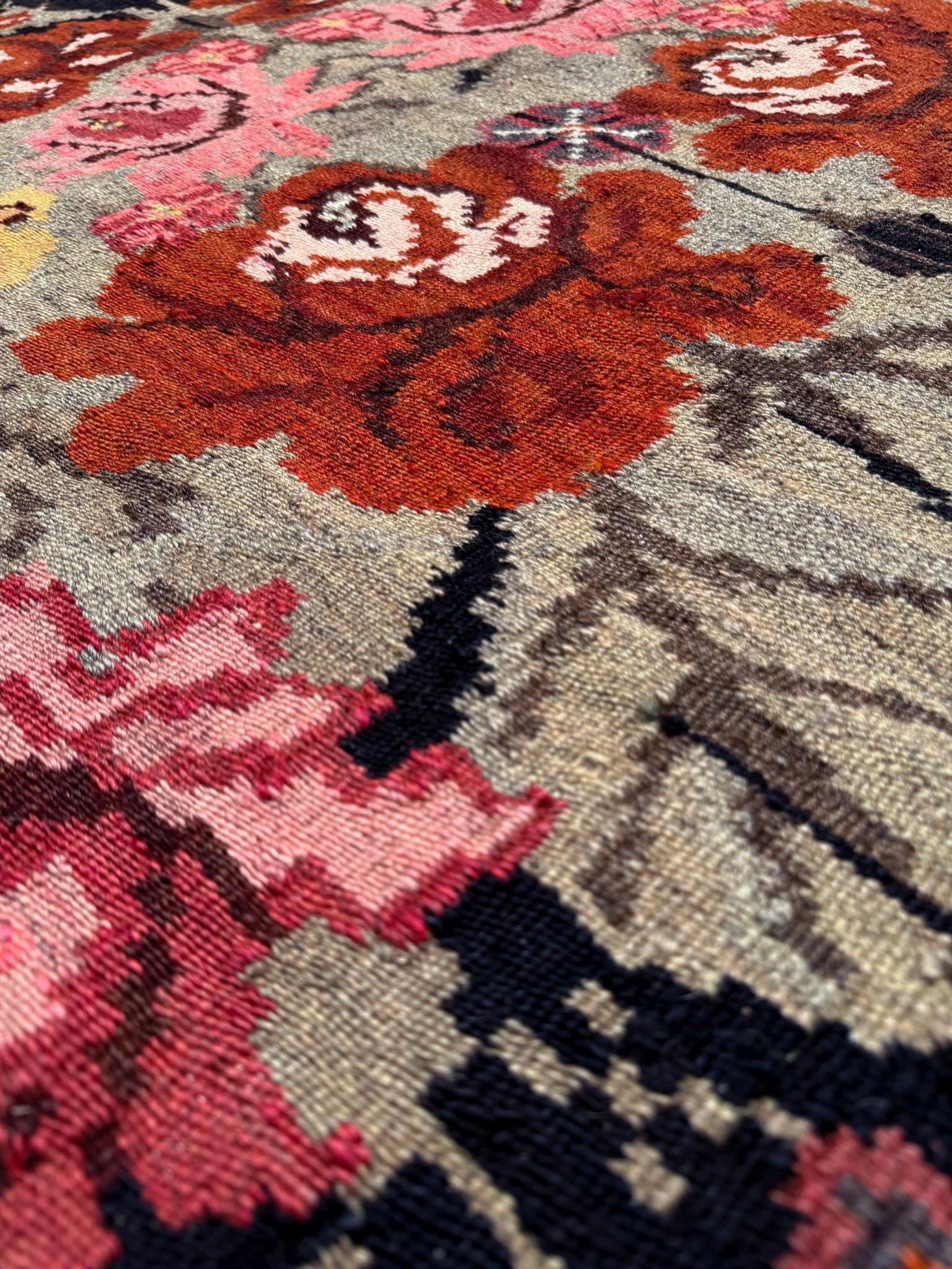 Meet the “Midnight Rose Bloom” — a stunning vintage Moldovan kilim that dances with both charm and boldness. Woven by hand in the 1950s, this 8×11 flatweave bursts with deep charcoal tones, rich terracotta, faded gold, and every shade of rose