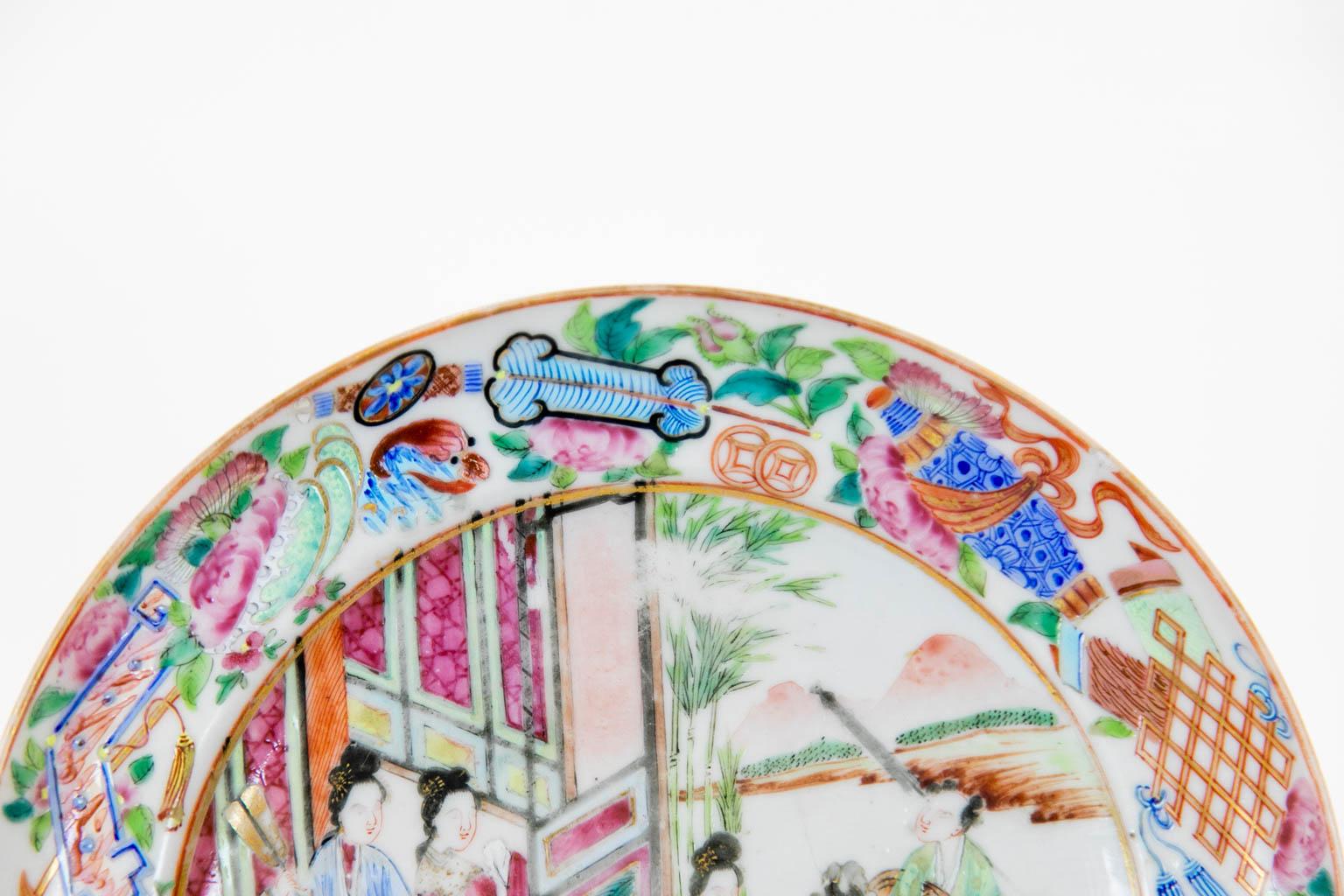 This plate has a center panel with Mandarin court scenes framed by a border with scrolls, interlaced marquis, and marine motifs. It has a very tiny frit chip on the inside rim.