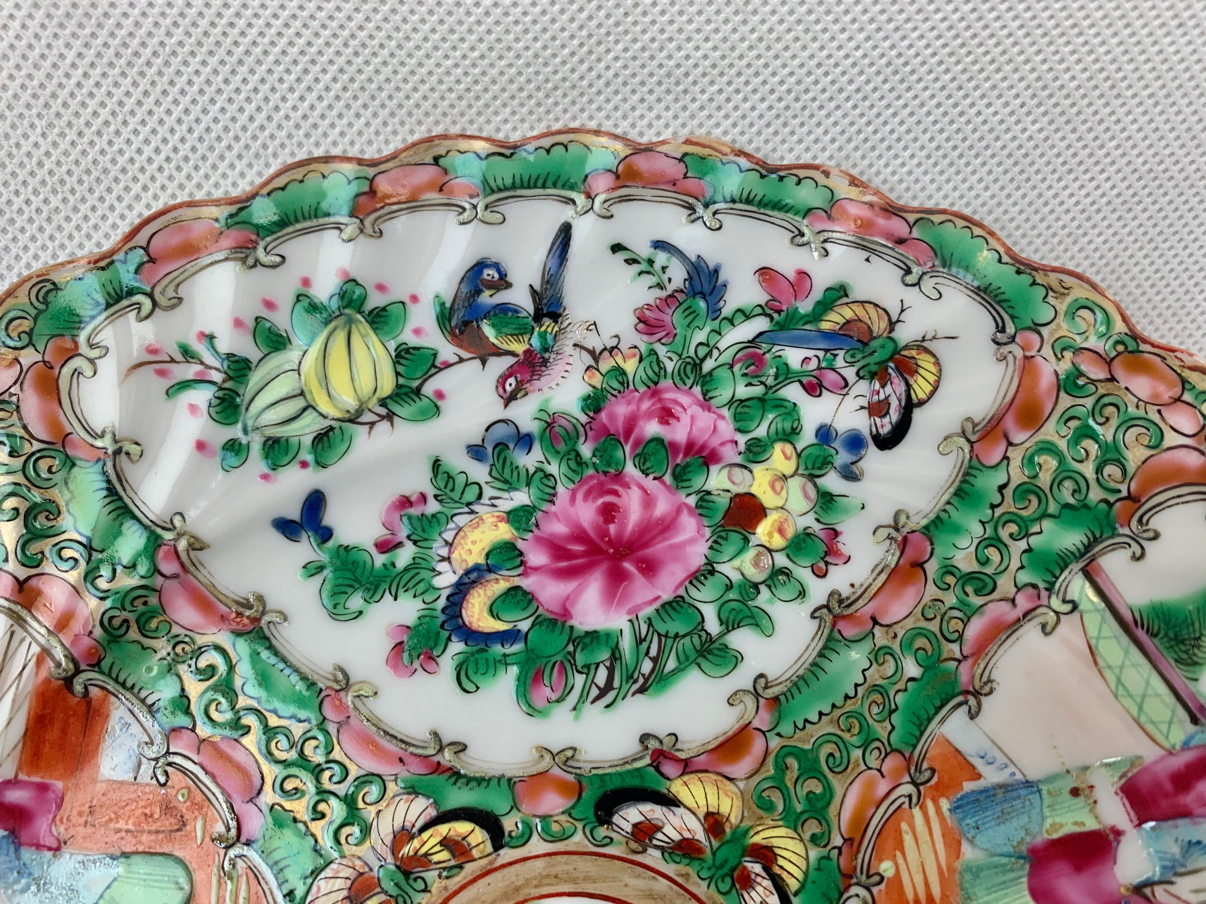 Chinese Export scalloped edge porcelain plate in the Rose Medallion style. Hand decorated in lively pastel colors on a plate form with a swirled design. The plate is divided into four quadrants, two with people and two with flowers and birds. There