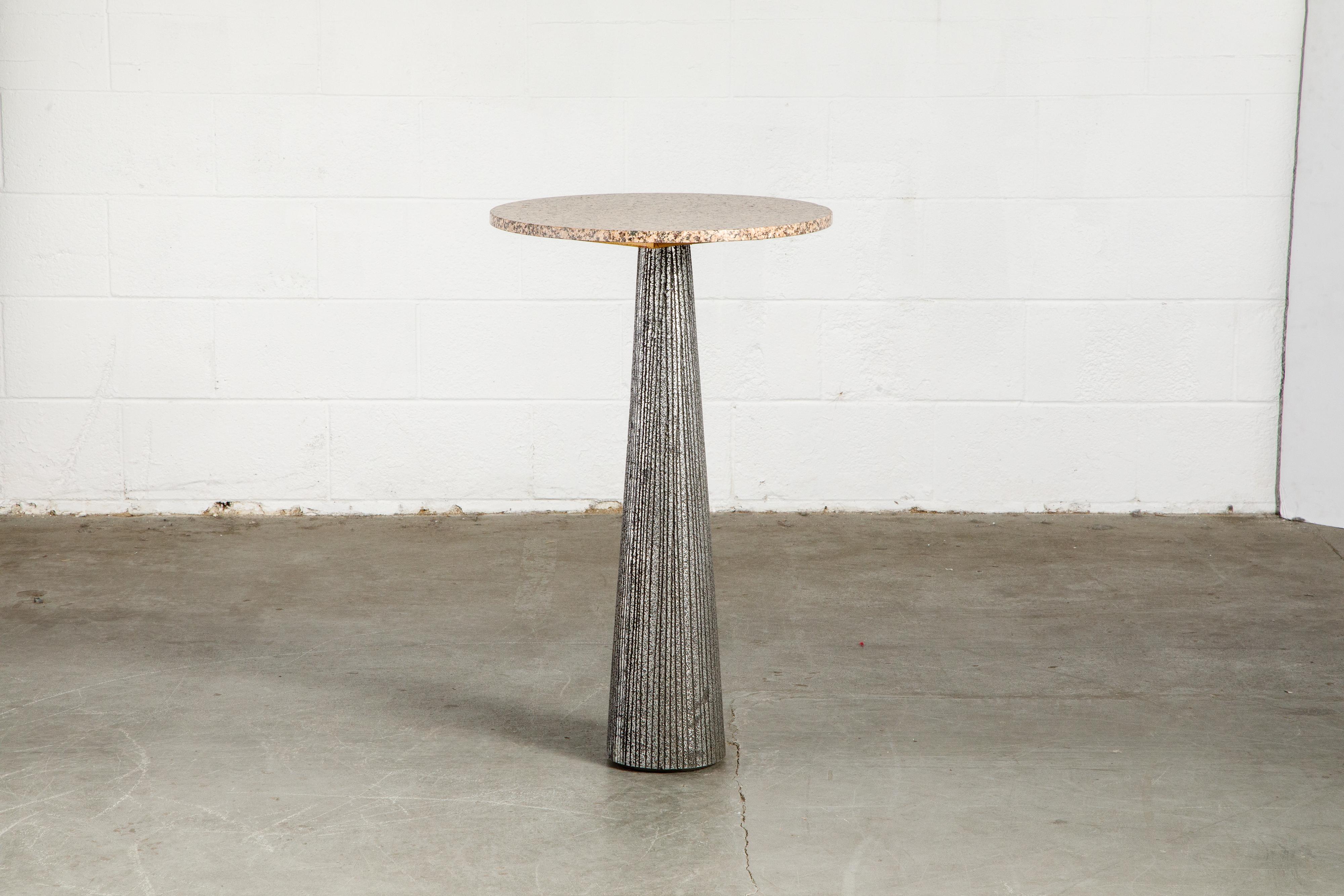 An incredible Brutalist occasional table with a beautiful rose pink granite top and a Brutalist enameled aluminum pedestal base by Forms + Surfaces, circa 1968. This spectacular piece is tall, allowing you to use it in a lot of ways that shorter