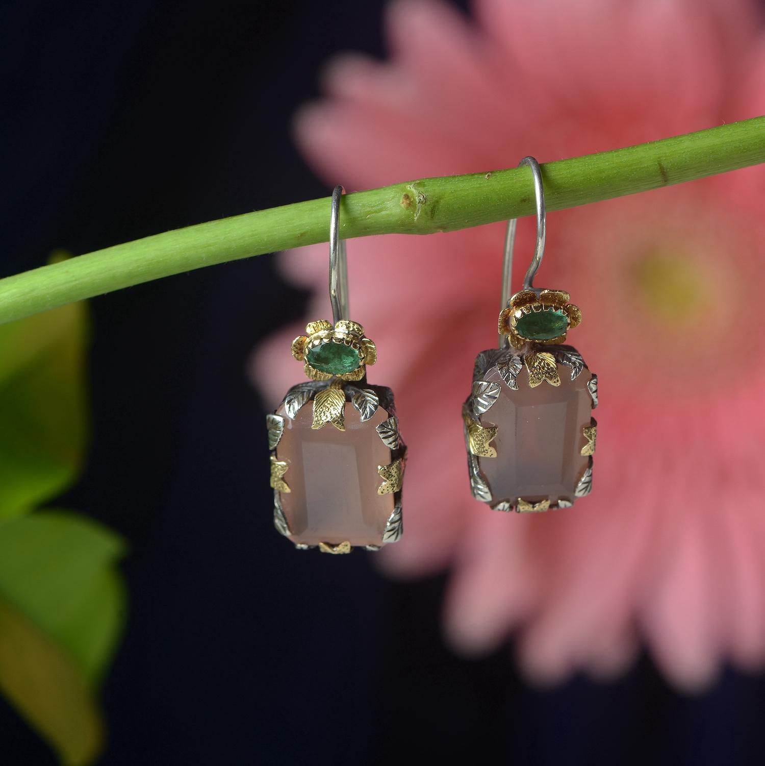 

These divine one-of-a-kind earrings have been handmade in our workshops. They feature hand cut rose quartz capped with emeralds, which are set in 18k gold and oxidized hand-engraved leaf motifs. The earrings have a safety catch at the back.

They