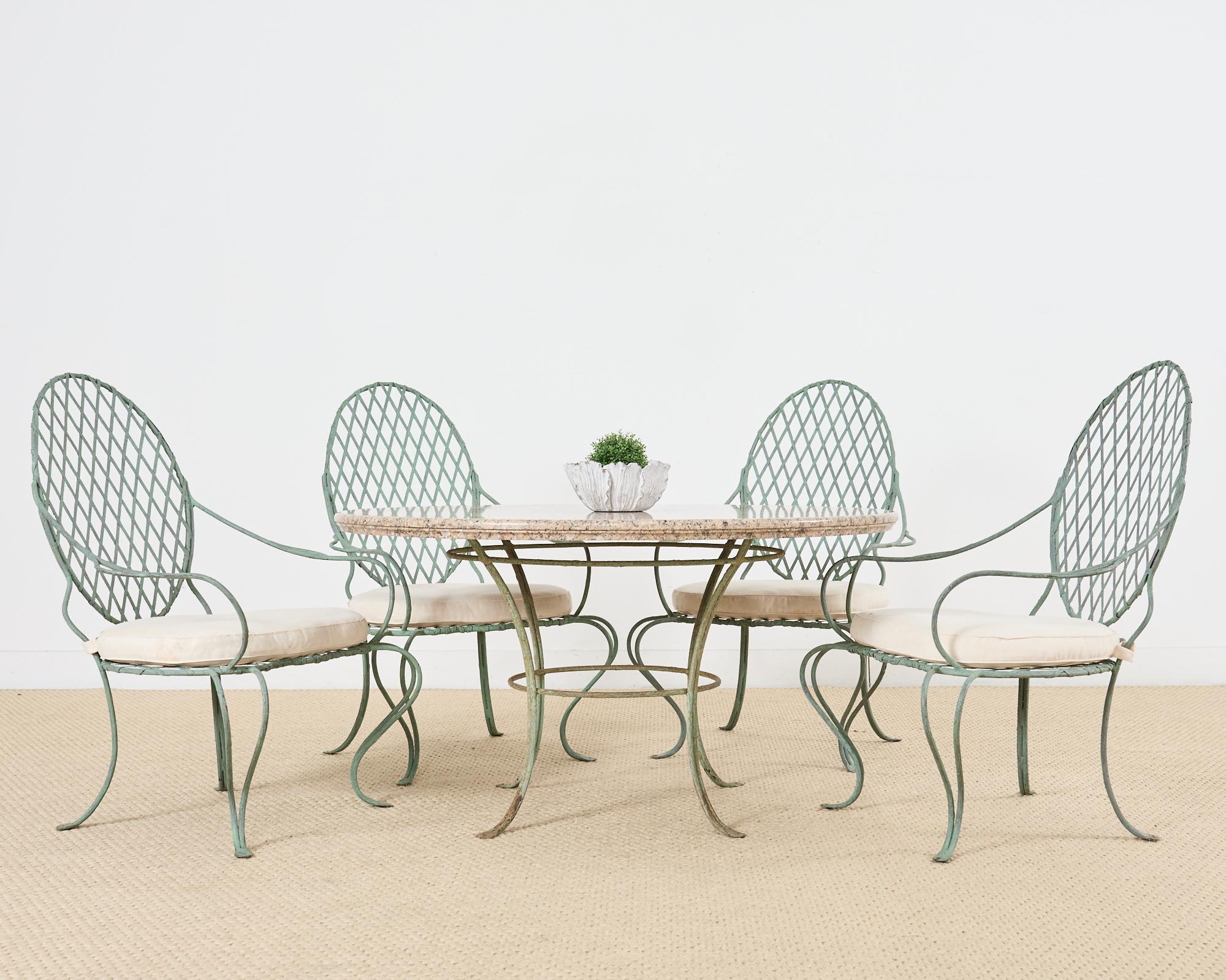 Icónico conjunto de comedor para patio y jardín compuesto por cuatro sillones de hierro y uno  Mesa de comedor redonda con tapa de piedra de 53,5 pulgadas de diámetro. El diseño de ramita de hierro de Rose Tarlow está fabricado en hierro artesanal