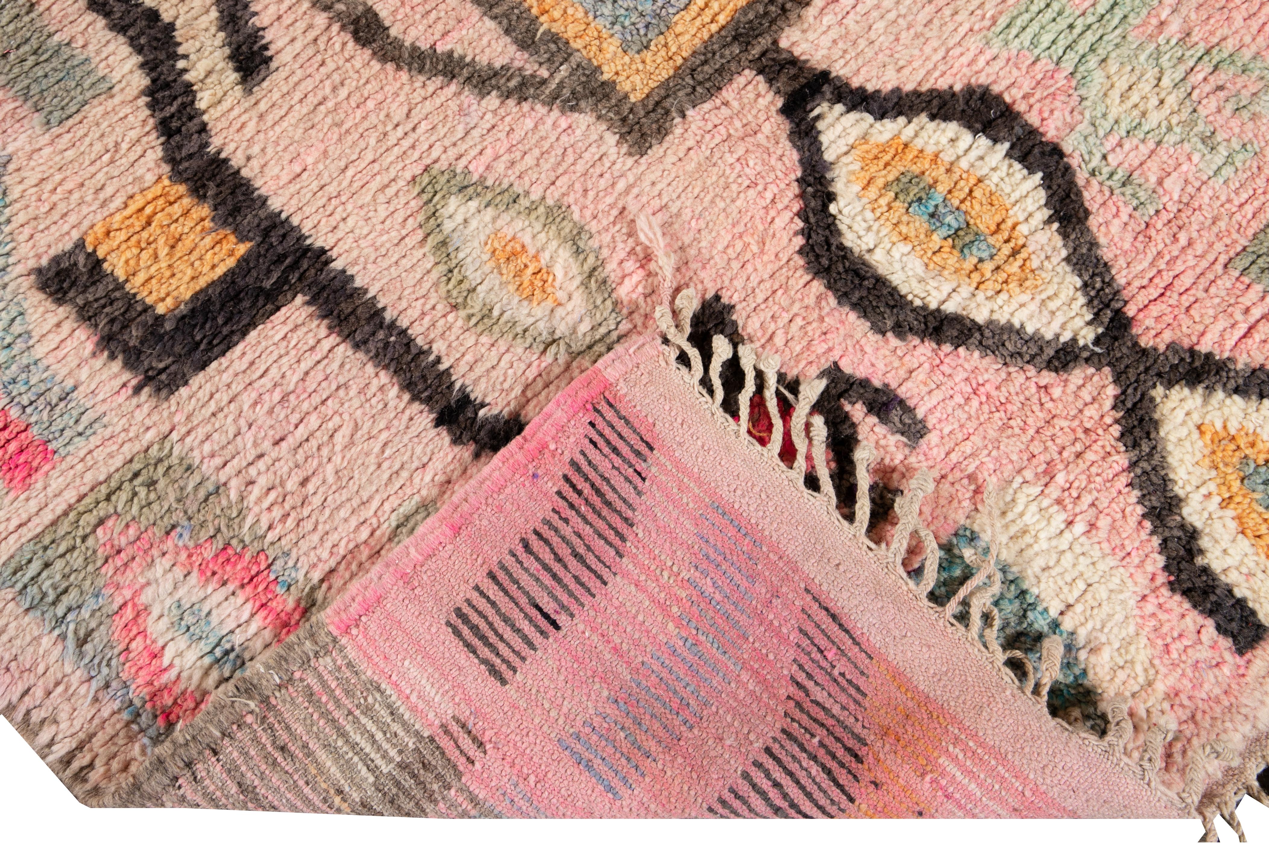 Beautiful vintage Azilal Moroccan hand knotted wool rug with the pink field. This Moroccan rug has a multi-color accent in all-over abstract patterns with different Berber symbols and geometric-based designs.

 This rug measures 4'10