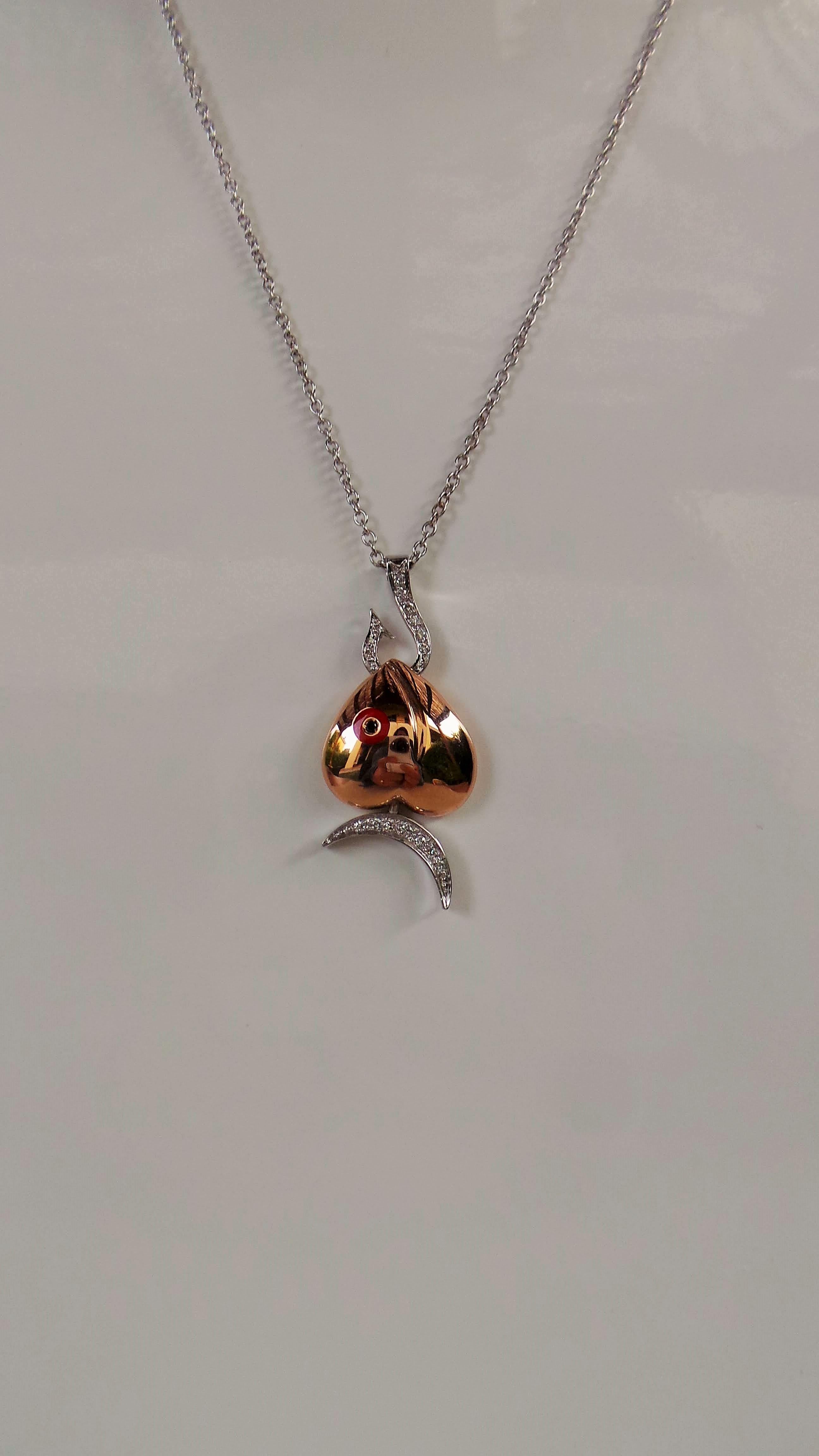 Andrea Macinai created this enamelled design for pendant and hand-set stones with white and black diamonds cut brillant.
This enchanting pendant necklace is entirely handmade in white and rose gold. Black diamond 0.015 carat in the eye of the fish,