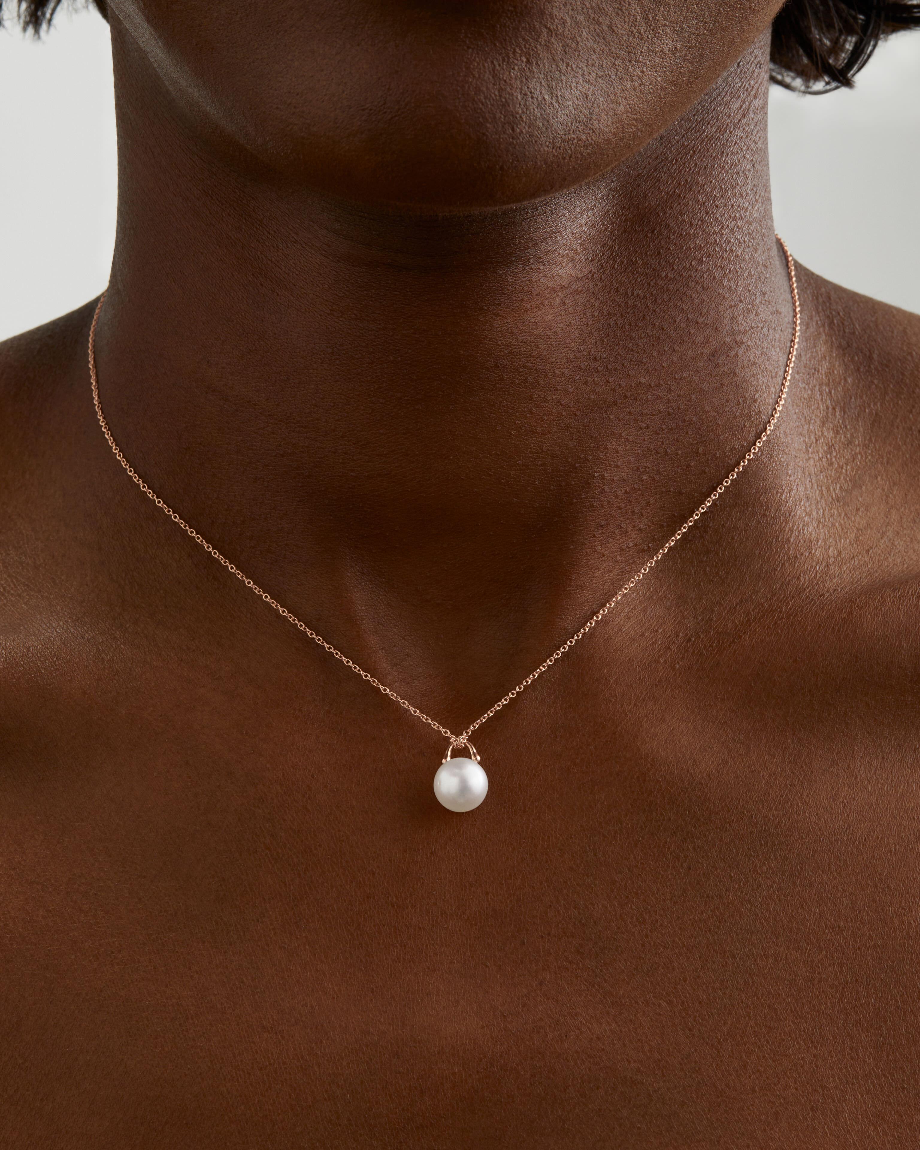 This unique pearl pendant by Roseate Jewelry features a single natural color round 12mm Austrailian South Sea pearl pendant framed in a setting with the structure of a padlock and the fluidity of water drops. Suspended from a delicate 18k rose gold