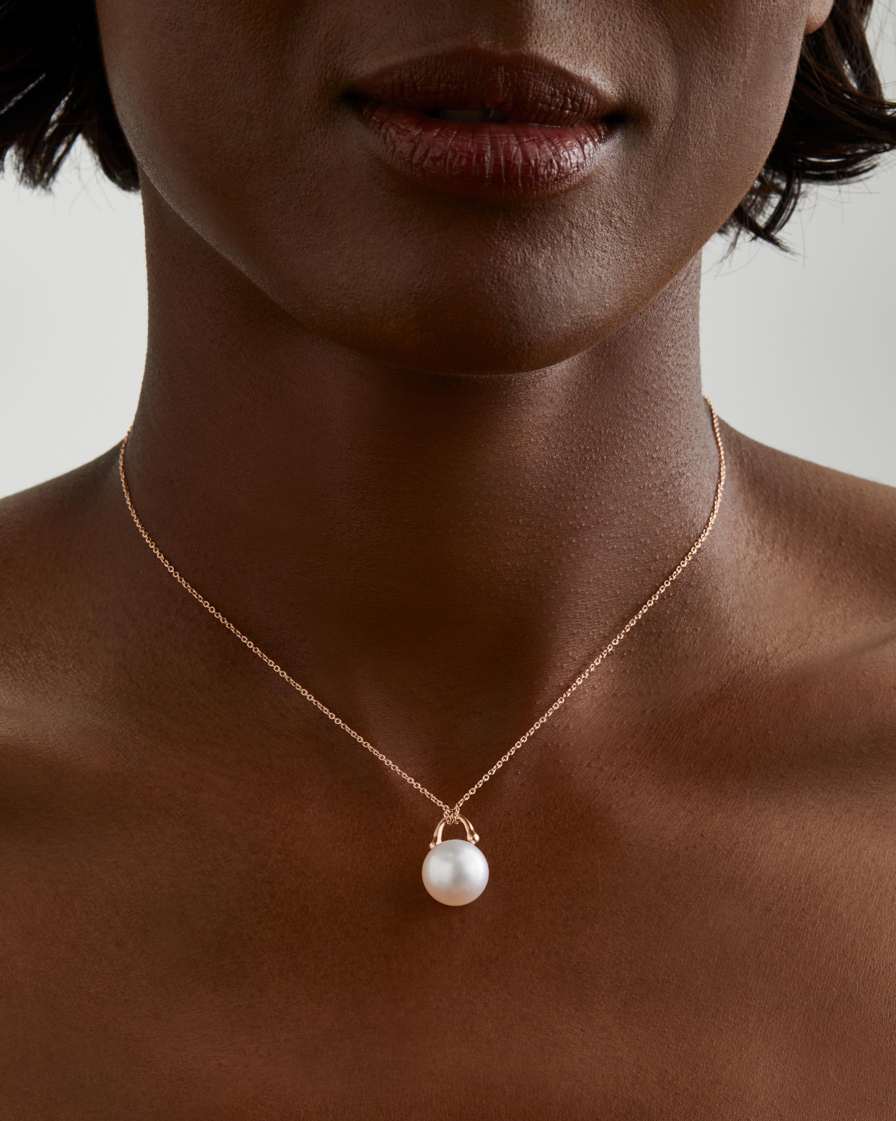 This unique pearl pendant by Roseate Jewelry features a single natural color round 12mm Austrailian South Sea pearl pendant framed in a setting with the structure of a padlock and the fluidity of water drops. Suspended from a delicate 18k rose gold