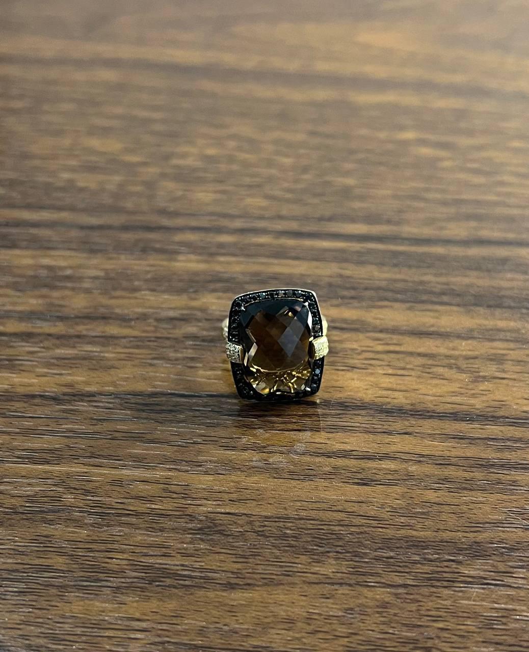 14k Gold Smoky Quartz and Diamond Ring. This exquisite ring features a large, faceted smoky quartz gemstone set in a 14k gold band. The gemstone is framed by a halo of small diamonds, enhancing its rich, warm tones. The ring is in excellent