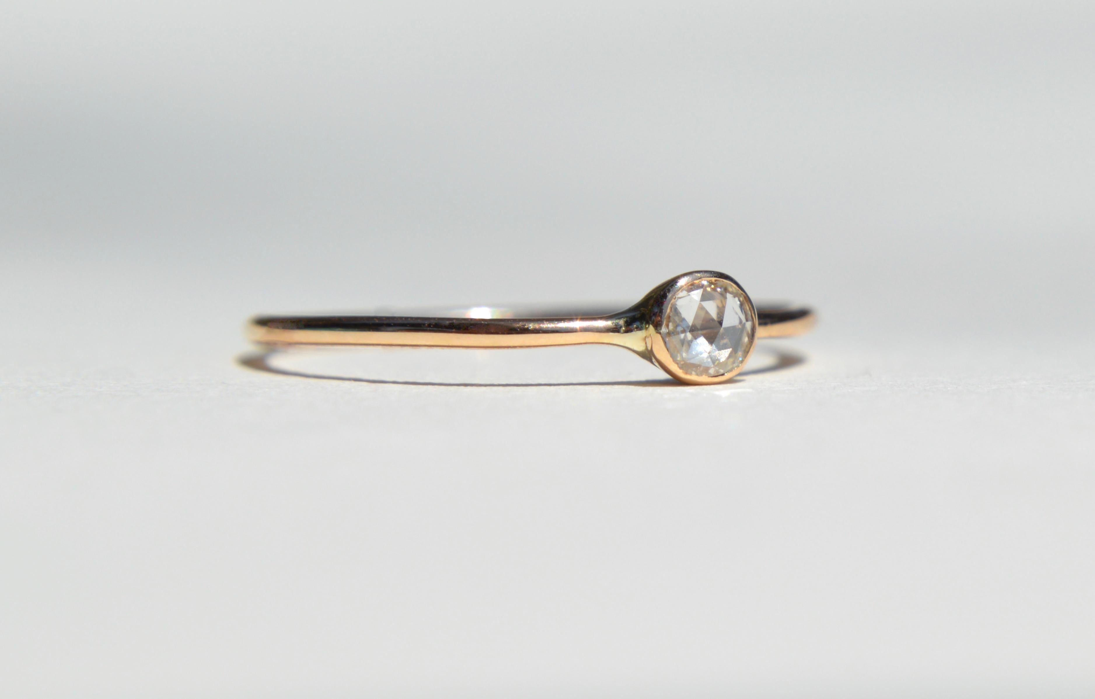 Minimal and lovely .21 Carat rosecut diamond engagement ring set in 14K yellow gold. Diamond measures 4.5x3.5mm. Diamond has been graded as color E (near colorless), clarity VVS1 (very very slightly included). 1mm wide round delicate band. Size