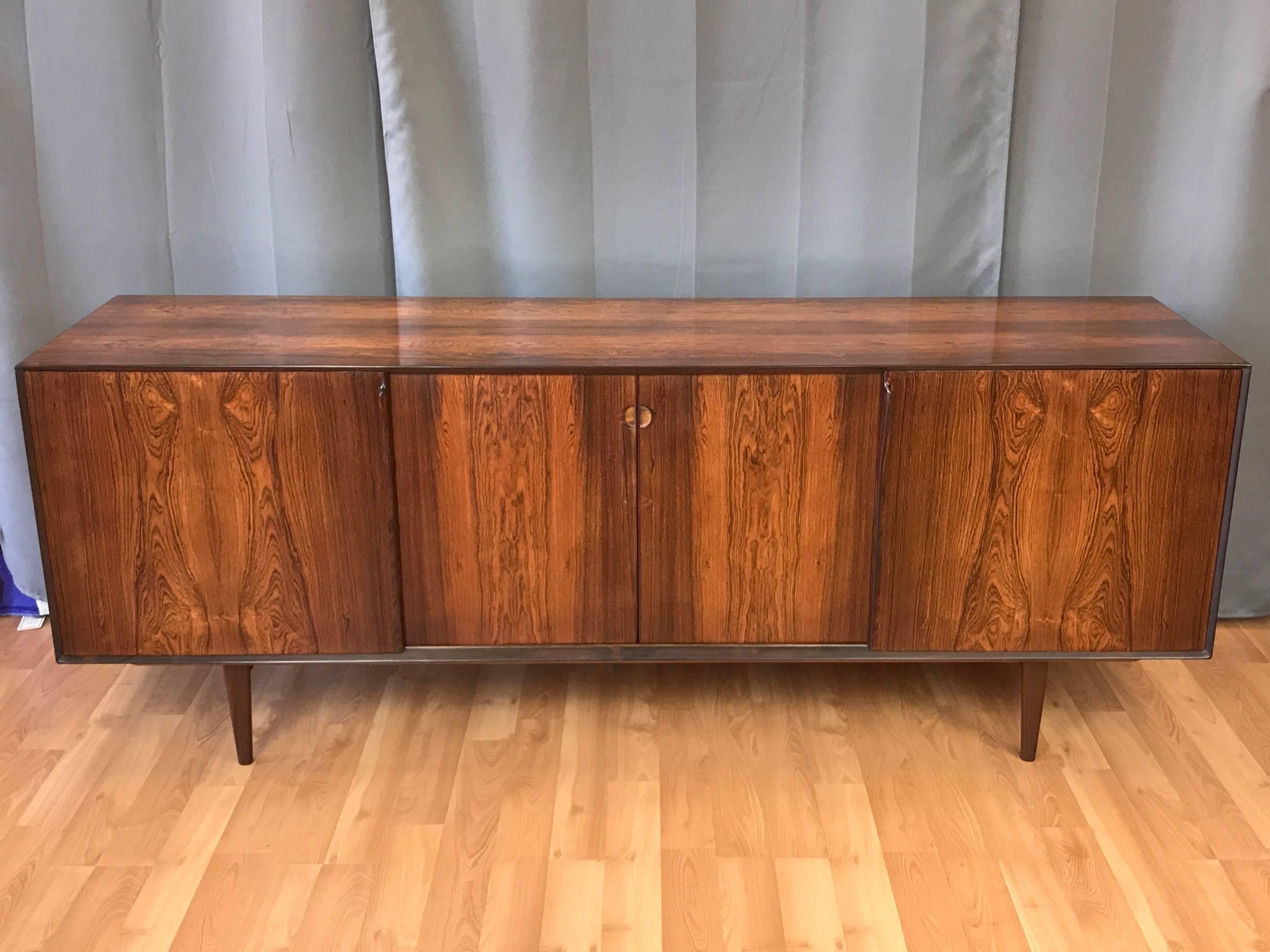 An incredibly handsome large rosewood sideboard or credenza with teak interior by Henry Rosengren Hansen for Brande Møbelindustri.

Exterior finished in nicely figured bookmatched rosewood veneer throughout. Solid rosewood beveled edge front