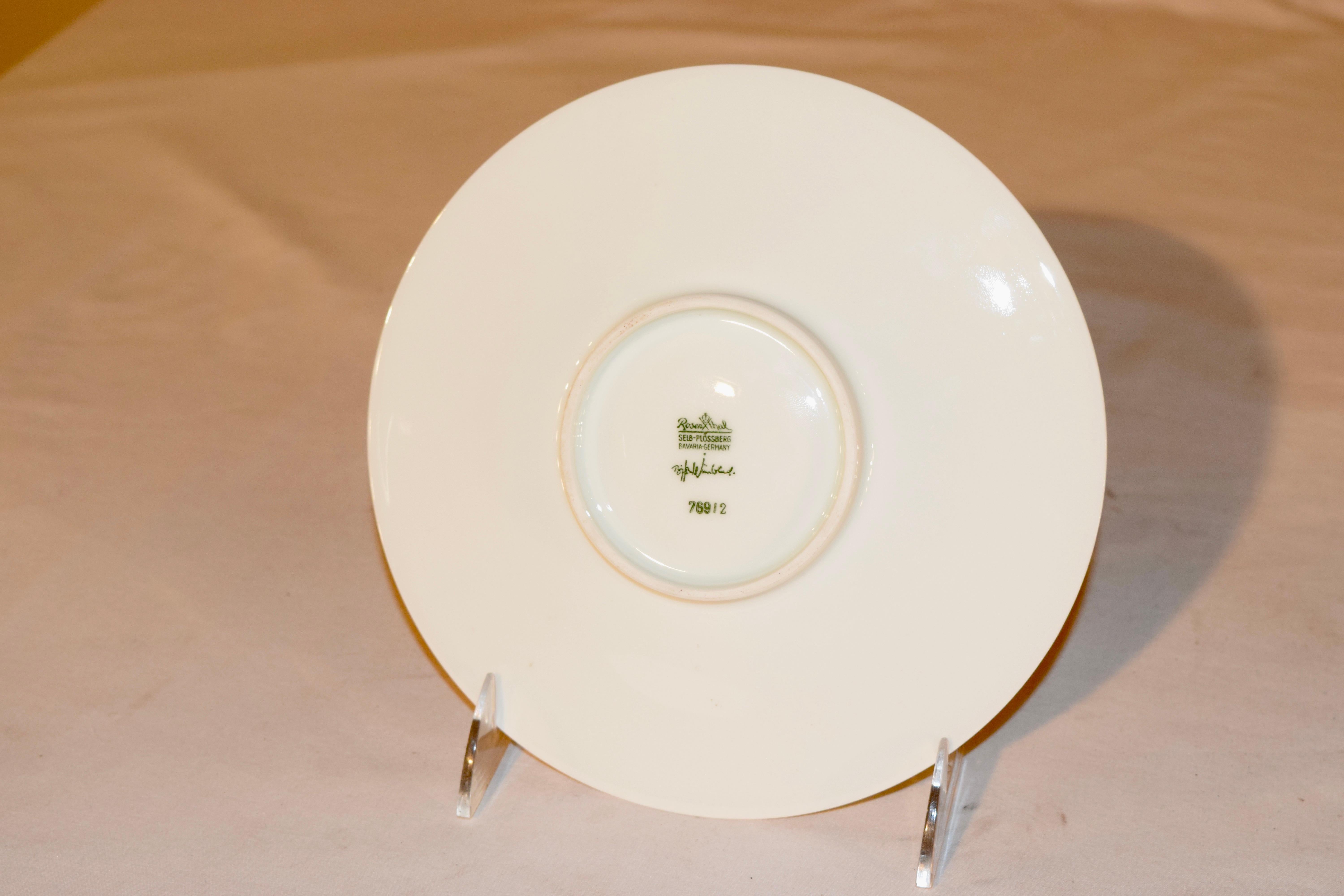 White porcelain decorative plate with raised matte dragonfly motif at rim surrounding a magical dragonfly catcher with net in the center. The brand stamp at underside, designed by Bjorn Wiinblad, manufactured by Rosenthal.
 